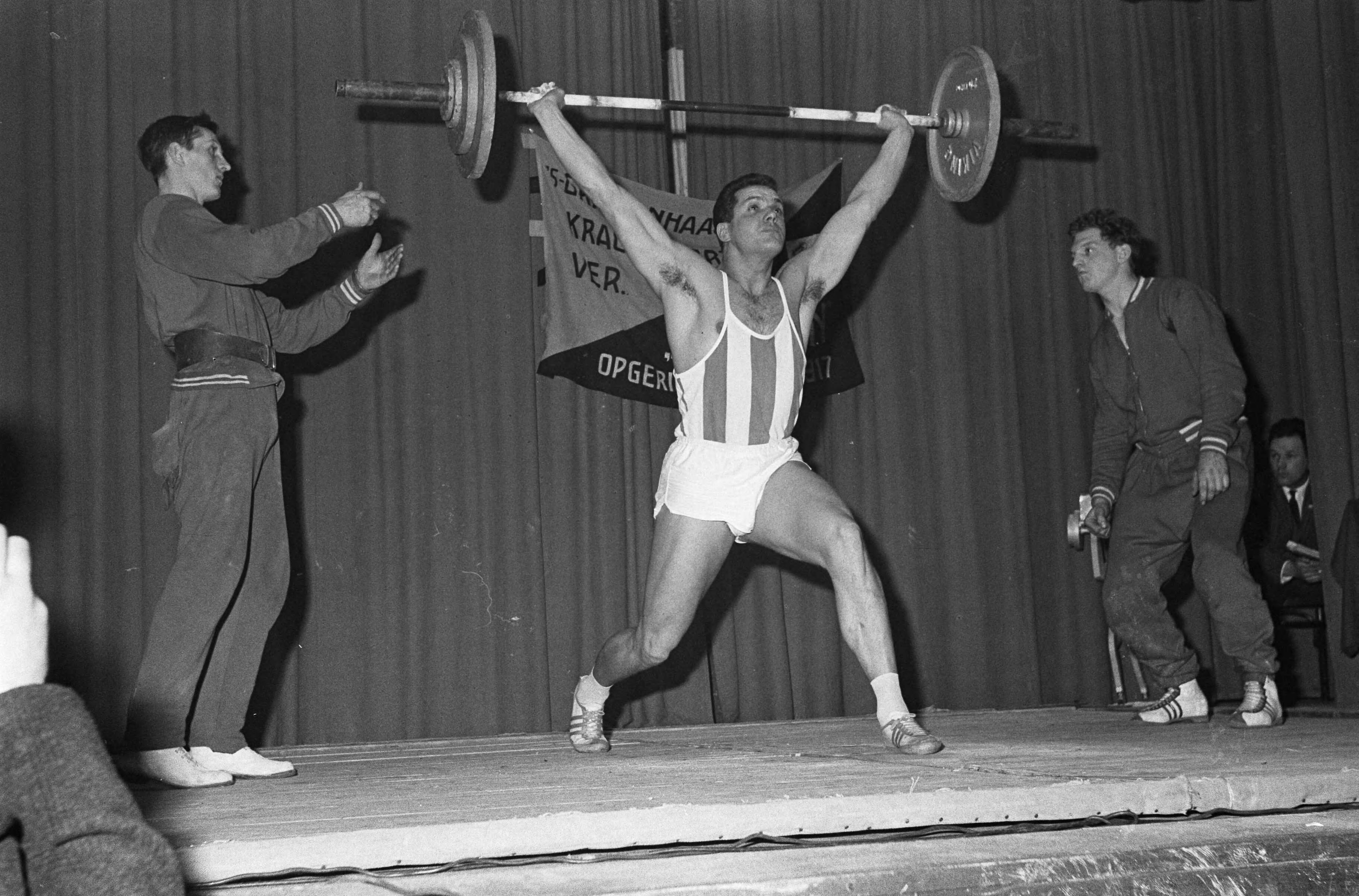 Fotocollectie Anefo — Eef Kamerbeek als gewichtheffer. Eef in aktie op he tNederlands kampioenschap gewichtheffen 2e klasse in Amicitia te Den Haag — Foto: Koch, Eric / Anefo. Licentie: Set B: Rechtenvrij / Publiek Domein. Bron: Nationaal Archief. http://hdl.handle.net/10648/aa293530-d0b4-102d-bcf8-003048976d84