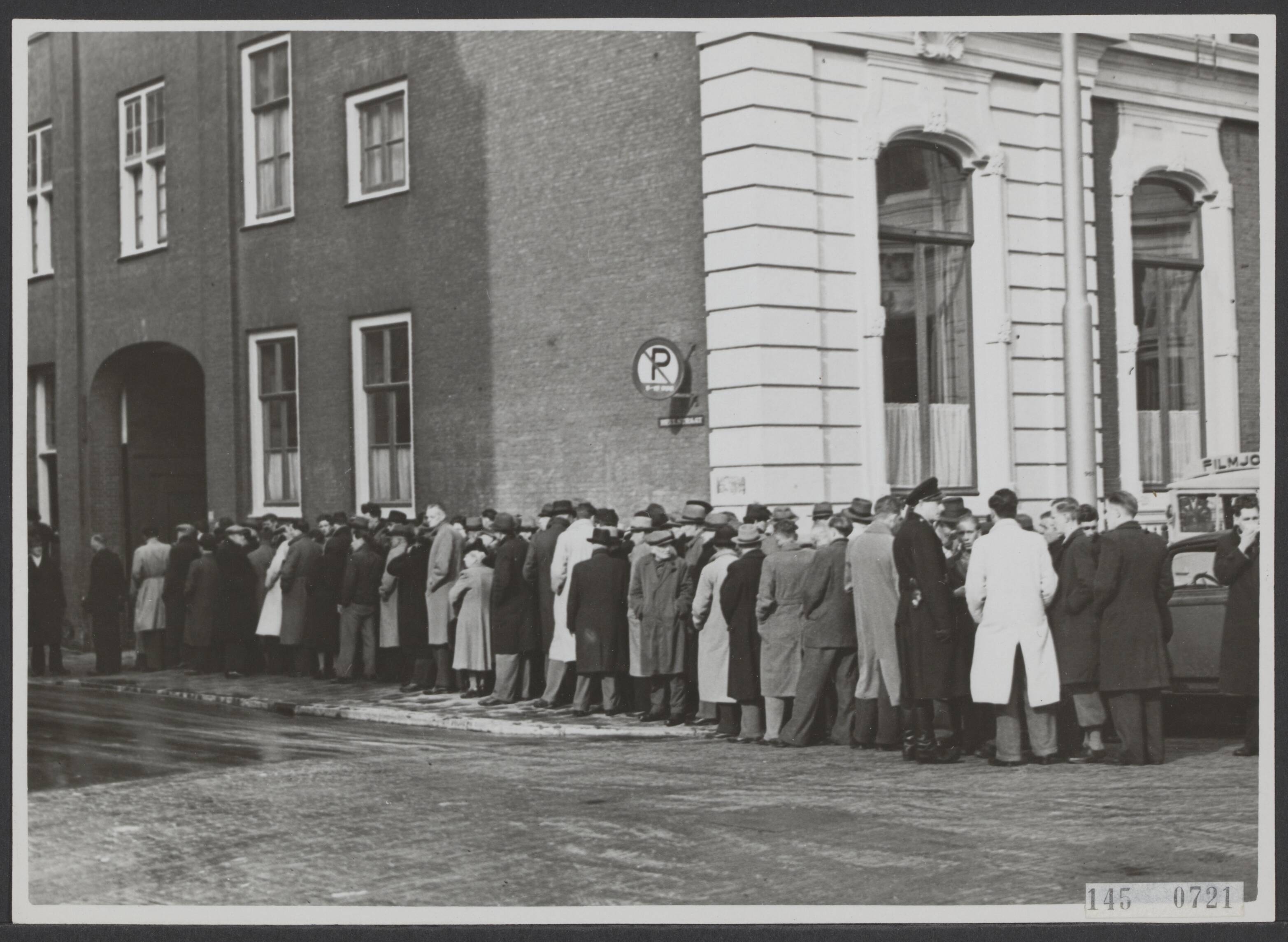 Fotocollectie Elsevier Binnenland — [Mensen, voornamelijk mannen, staan in een rij voor een gebouw in Den Haag. Rechts is nog een voertuig van het "Filmjournaal" te zien] — Foto: Fotopersbureau Van den Heuvel. Licentie: Set B: Rechtenvrij / Publiek Domein. Bron: Nationaal Archief. http://hdl.handle.net/10648/ae404f28-d0b4-102d-bcf8-003048976d84