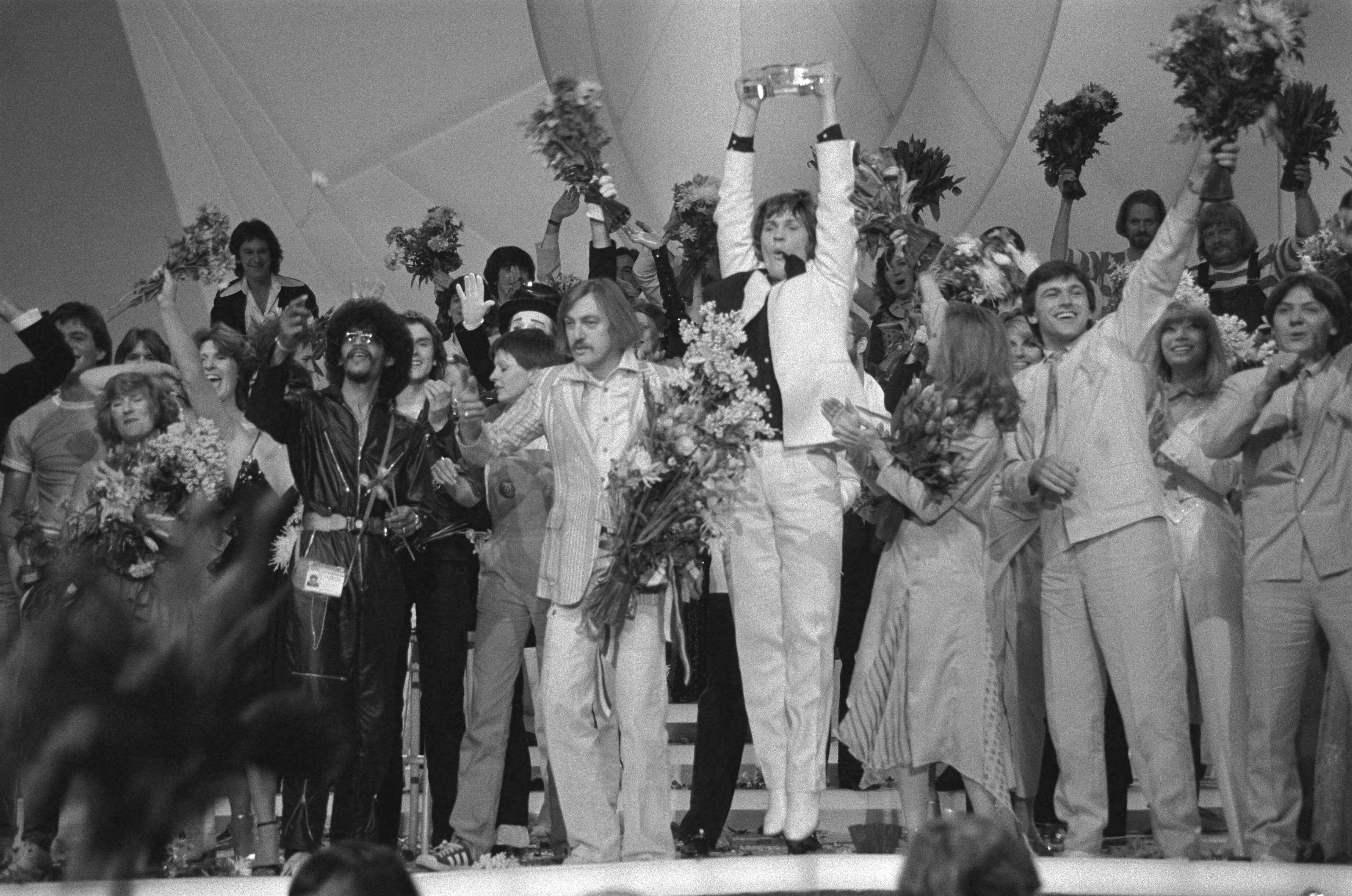 Eurovisie Songfestival 1980 — Eurovisie Songfestival 1980 (Den Haag); winnaar Johnny Logan (Ierland) in de bloemen — Foto: Dijk, Hans van / Anefo. Licentie: Set B: Rechtenvrij / Publiek Domein. Bron: Nationaal Archief. http://hdl.handle.net/10648/acde79fc-d0b4-102d-bcf8-003048976d84