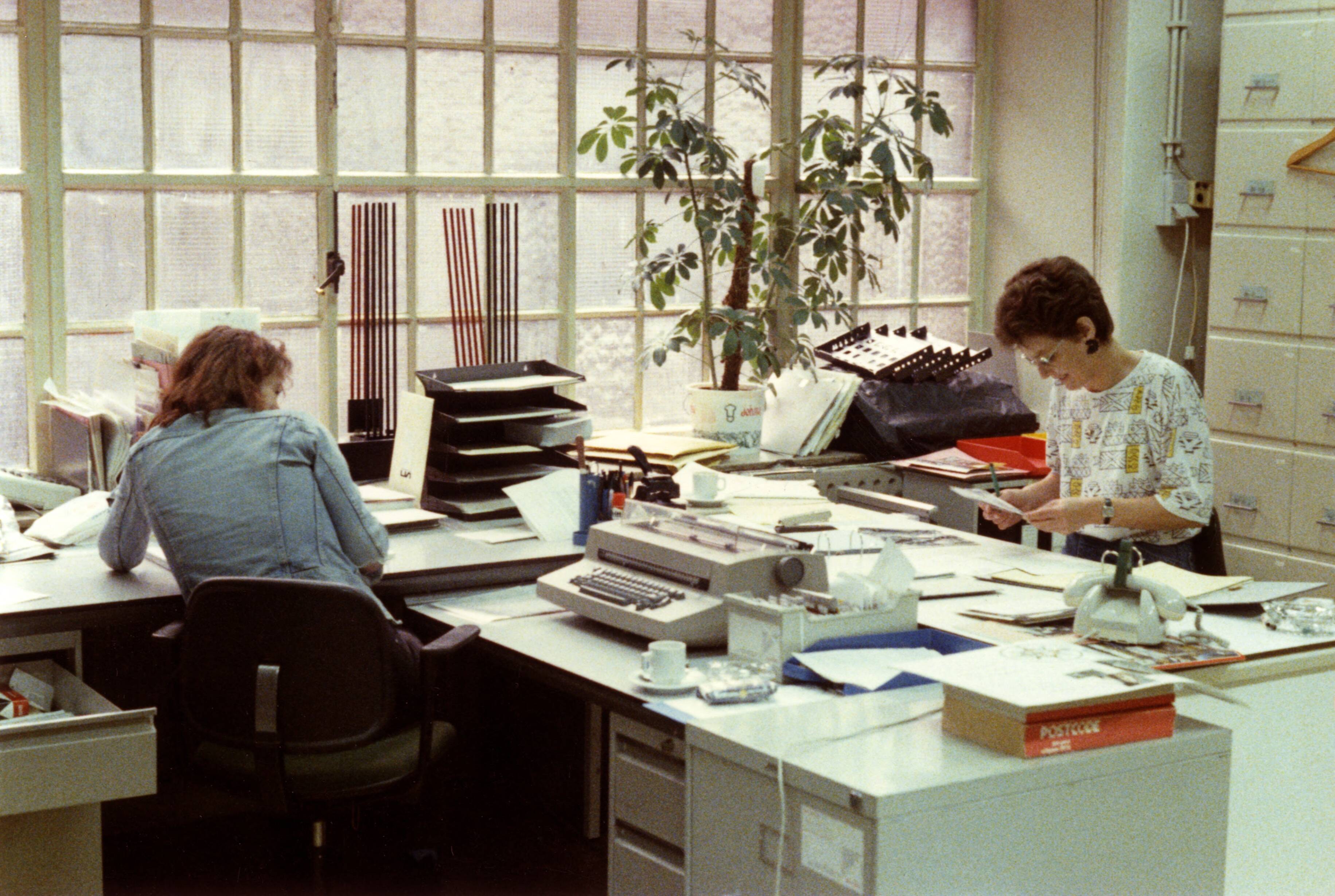 "Economie, handel, industrie, bouw, arbeid", Cultuur — Medewerkers van de administratie van Spaarnestad Fotoarchief (Spaarnestad Photo), in de eerste vestiging van de stichting, in het voormalige complex van Johan Enschedé in Haarlem, Nederland. zonder datum [omstreeks 1992] — Foto: Graaf, Willem de / Spaarnestad Photo (05887). Licentie: Set B: Rechtenvrij / Publiek Domein. Bron: Nationaal Archief. http://hdl.handle.net/10648/35429da6-cbf3-a382-e063-6df0900a6686