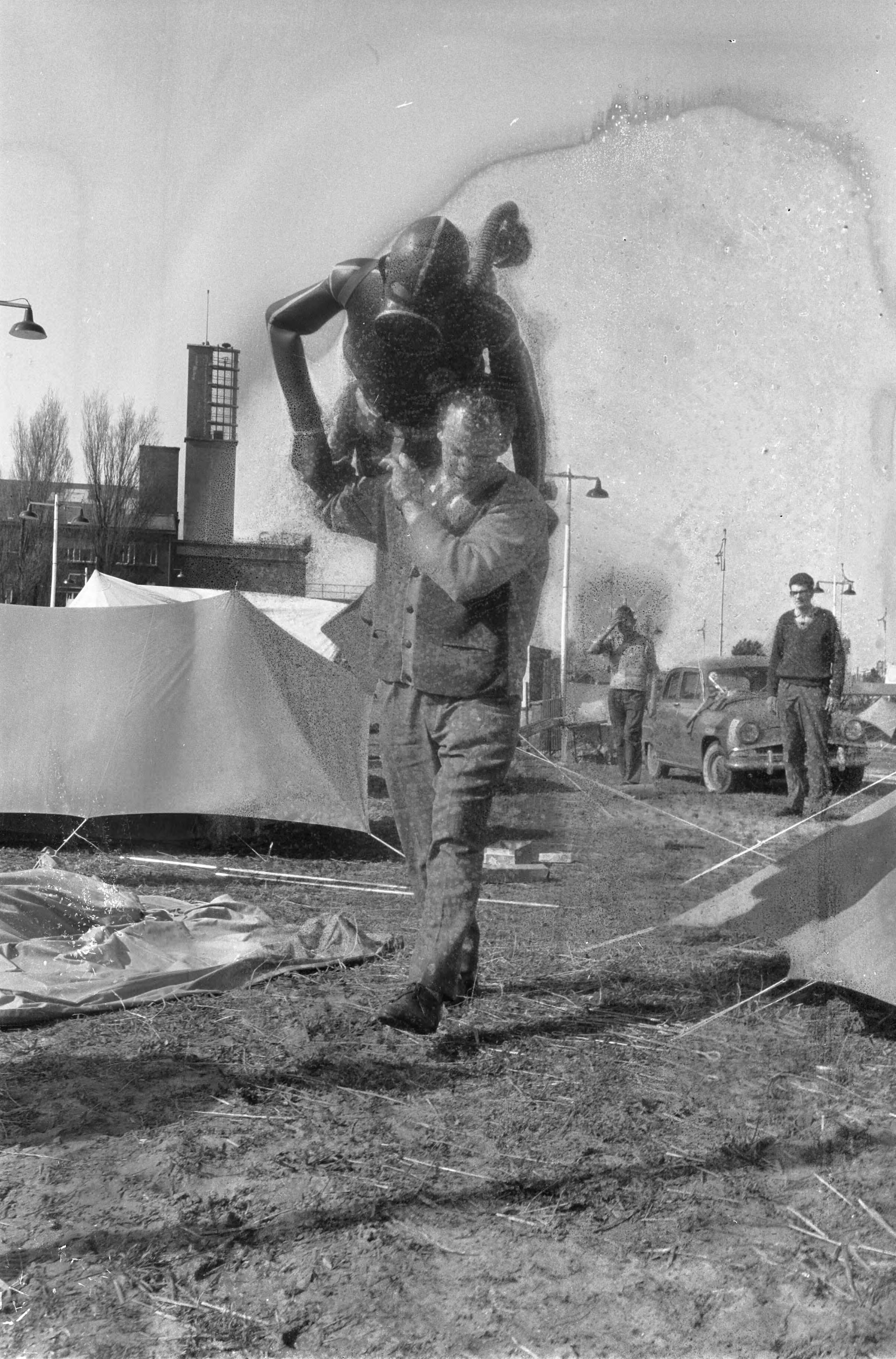 Fotocollectie Anefo — Inrichten tentoonstelling "Goed Kamp" in de Houtrusthal in Den Haag. Man loopt met pop aangekleed als duiker (kikvorsman) op zijn rug over het buitenterrein — Foto: Pot, Harry / Anefo. Licentie: Set B: Rechtenvrij / Publiek Domein. Bron: Nationaal Archief. http://hdl.handle.net/10648/a9d00af0-d0b4-102d-bcf8-003048976d84