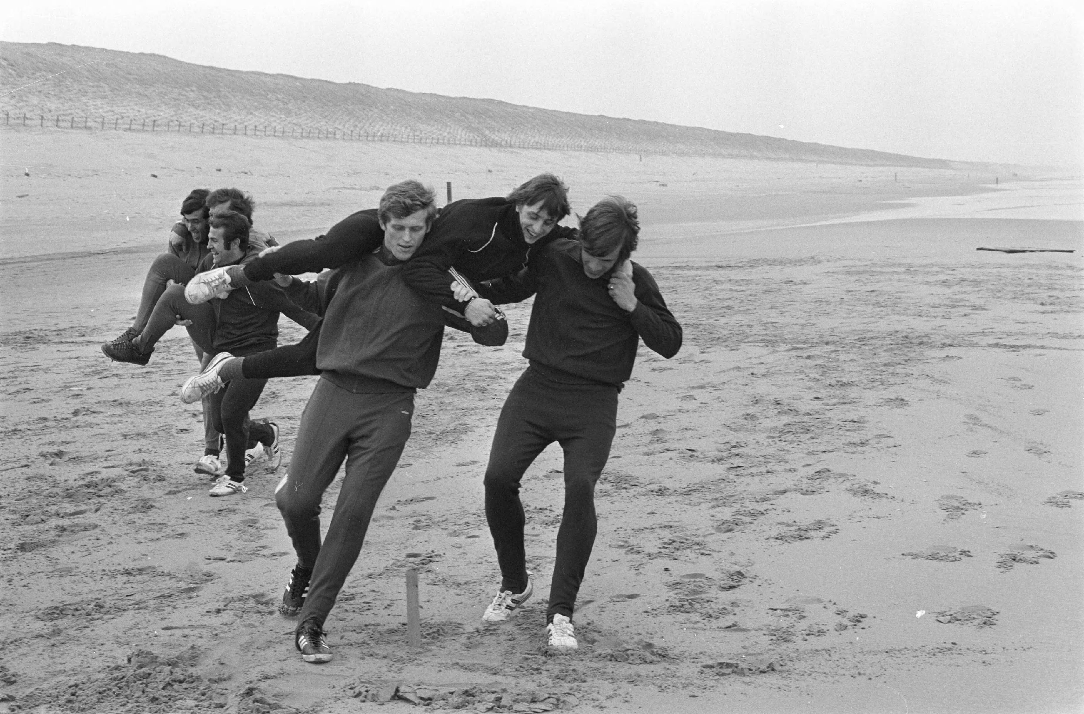Training van Ajax in de duinen en op het strand bij Wassenaar ter voorbereiding voor de wedstrijd tegen Arsenal — De voetballers Keizer en Van Dijk nemen Cruijff op de schouders — Foto: Fotograaf Onbekend / Anefo. Licentie: Set B: Rechtenvrij / Publiek Domein. Bron: Nationaal Archief. http://hdl.handle.net/10648/ab940a30-d0b4-102d-bcf8-003048976d84