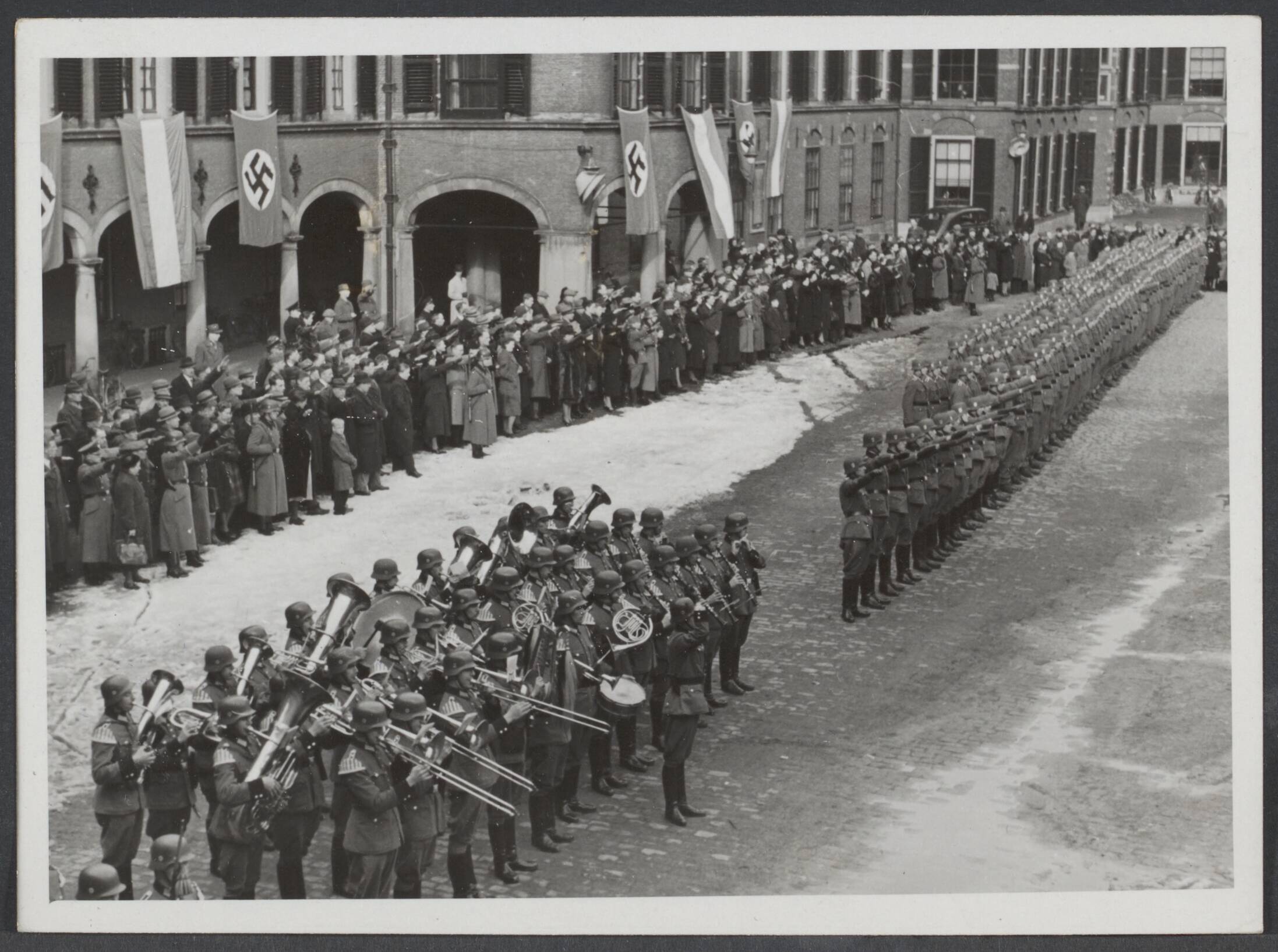 Nederlandse S.S. (Waffen SS.) — Beëdiging van de de Nederlandse ambulance die naar het Oostfront zla vertrekken op het Binnenhof te Den Haag. Het spelen der volksliederen — Foto: Meijer, T.A. / N.V. Polygoon. Licentie: Set B: Rechtenvrij / Publiek Domein. Bron: Nationaal Archief. http://hdl.handle.net/10648/897a30a7-af08-6035-772e-28612773facf