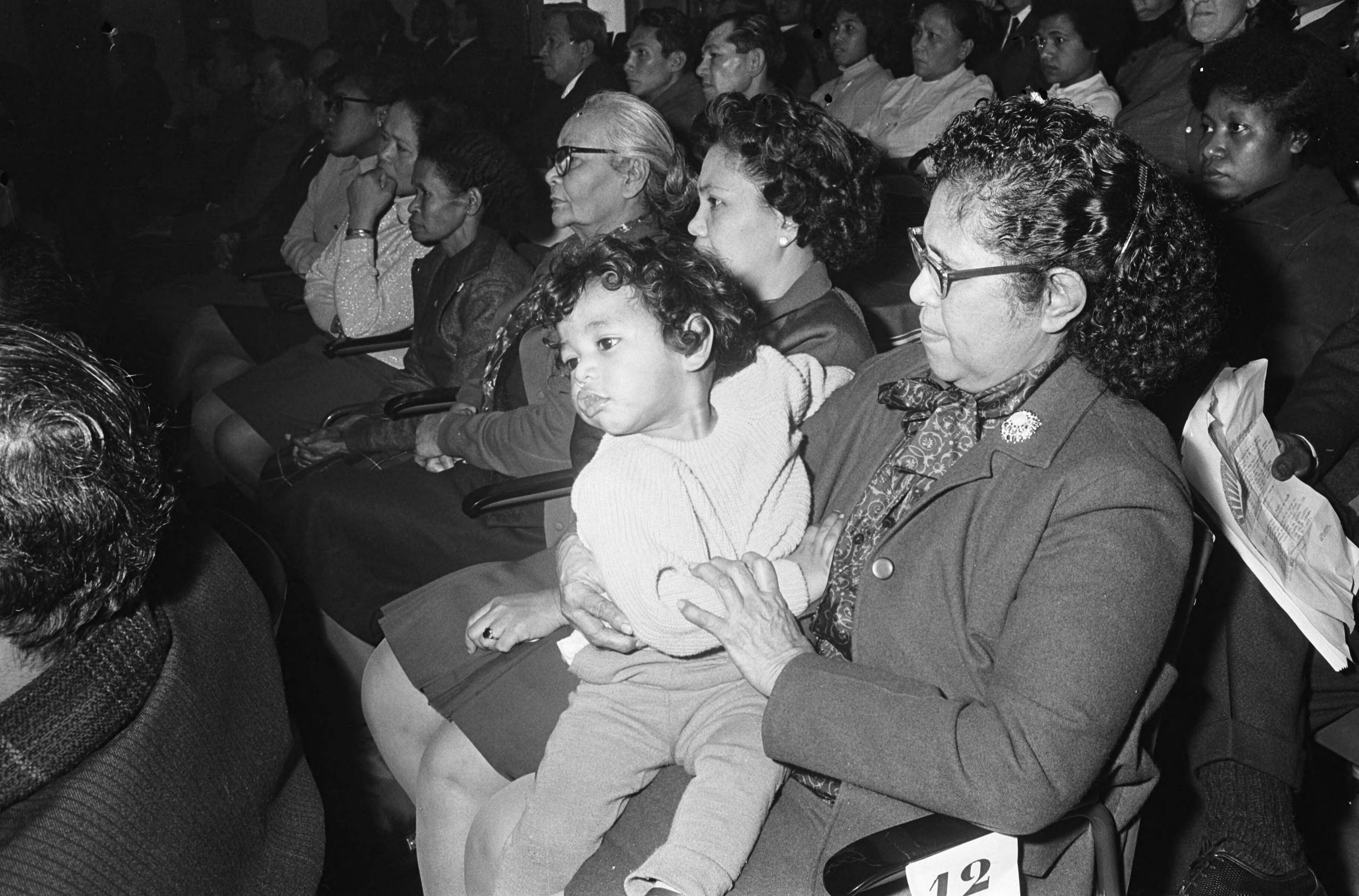 Fotocollectie Anefo — Jaarvergadering Papoeas in Scheveningen, kleine meid bij moeder op schoot — Foto: Koch, Eric / Anefo. Licentie: Set B: Rechtenvrij / Publiek Domein. Bron: Nationaal Archief. http://hdl.handle.net/10648/ab0dd8d4-d0b4-102d-bcf8-003048976d84