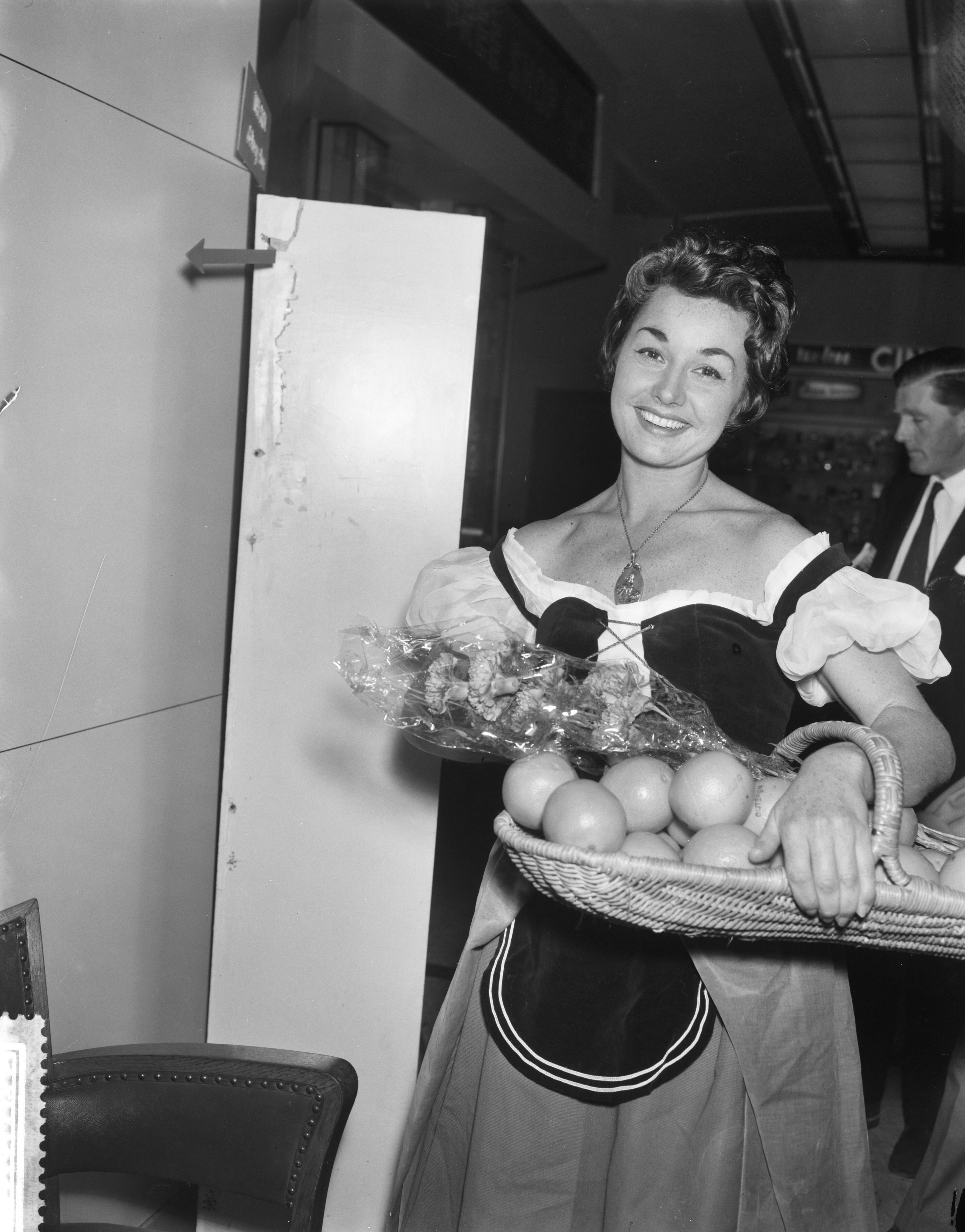 Fotocollectie Anefo — Aankomst Miss Sinaasappel (Nell Gwynn) uit Engeland op Schiphol. Miss Sinaasappel in de aankomsthal — Foto: Bilsen, Joop van / Anefo. Licentie: Set B: Rechtenvrij / Publiek Domein. Bron: Nationaal Archief. http://hdl.handle.net/10648/a9b8c962-d0b4-102d-bcf8-003048976d84