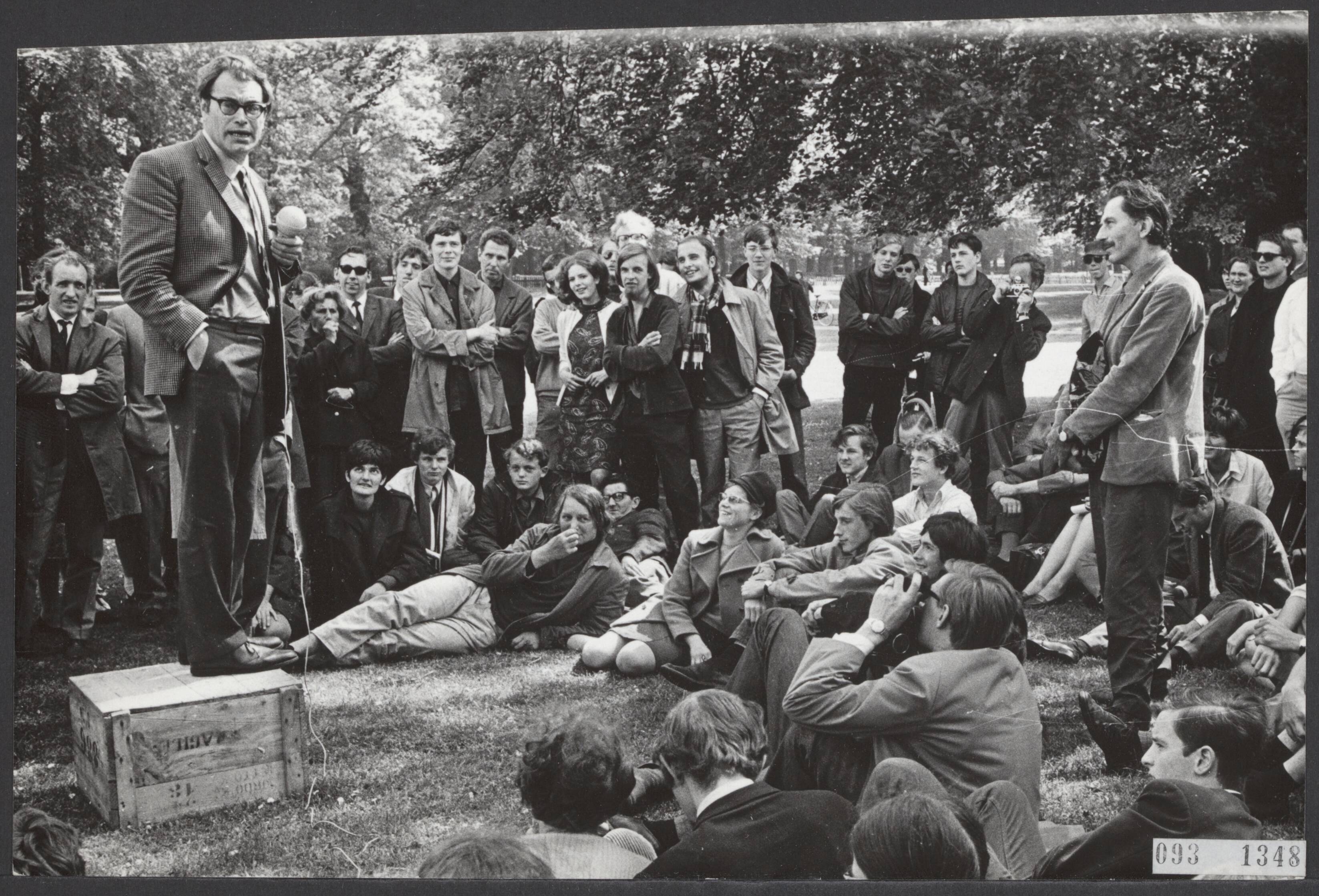 Fotocollectie Elsevier Binnenland — Speakerscorner in Haarlem op het Vlooienveld bij de Haarlemmerhout. Godfried Bomans was een der eerste sprekers. Zijn speech ging over de taalvernieuwing — Foto: Koch, Eric / Anefo. Licentie: Set B: Rechtenvrij / Publiek Domein. Bron: Nationaal Archief. http://hdl.handle.net/10648/ae2b1b30-d0b4-102d-bcf8-003048976d84