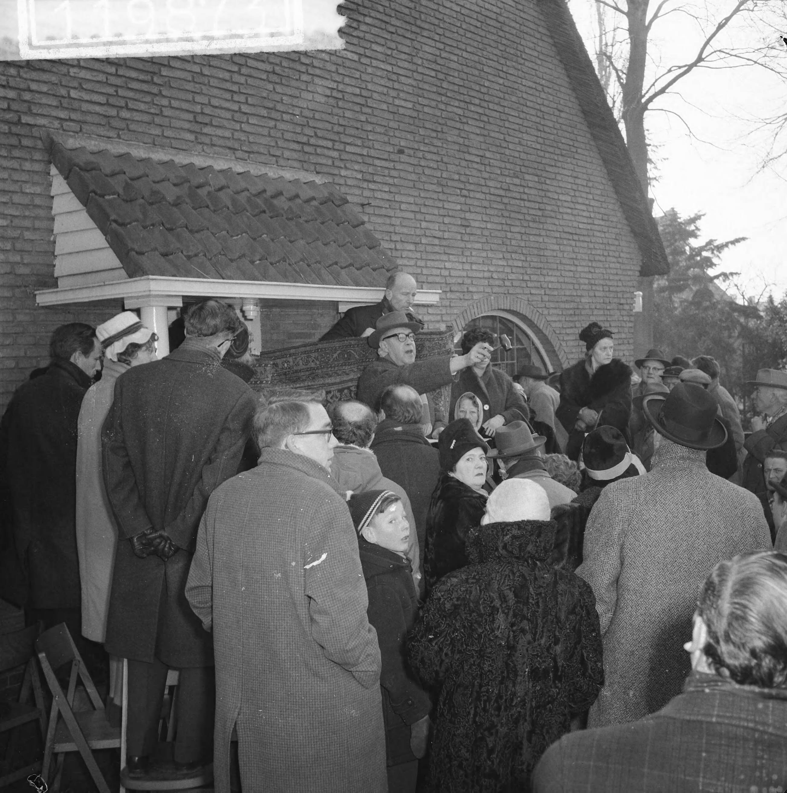 Fotocollectie Anefo — Veiling van de inboedel van Jolle Jansma te Bussum veilingknechten houden kleed op — Foto: Lindeboom, Henk / Anefo. Licentie: Set B: Rechtenvrij / Publiek Domein. Bron: Nationaal Archief. http://hdl.handle.net/10648/a9c5e3d6-d0b4-102d-bcf8-003048976d84