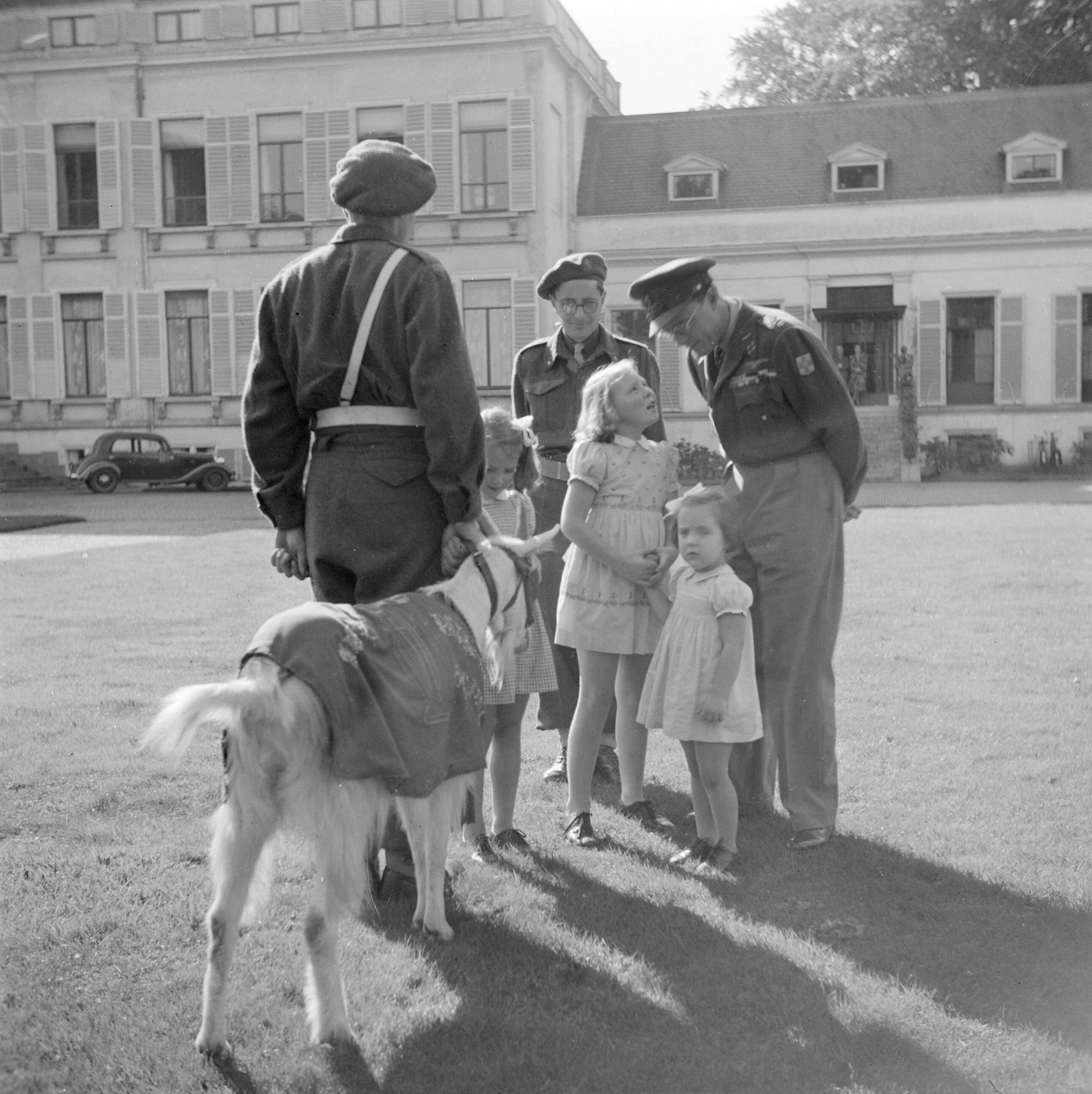 Afscheid in de voortuin van paleis Soestdijk van de Prins Bernhard Kapel met hun mascotte, de geit Kees, wegens vertrek naar Nederlands-Indië — prinsessen|paleizen|muziekkorpsen|prinsen|geiten|Paleis Soestdijk|Beatrix (prinses Nederland)|Irene (prinses Nederland)|Bernhard (prins Nederland)|Margriet (prinses Nederland)|Baarn|Utrecht (provincie)|koninklijk huis — Foto: Poll, Willem van de. Licentie: Set B: Rechtenvrij / Publiek Domein. Bron: Nationaal Archief. http://hdl.handle.net/10648/aee8939a-d0b4-102d-bcf8-003048976d84