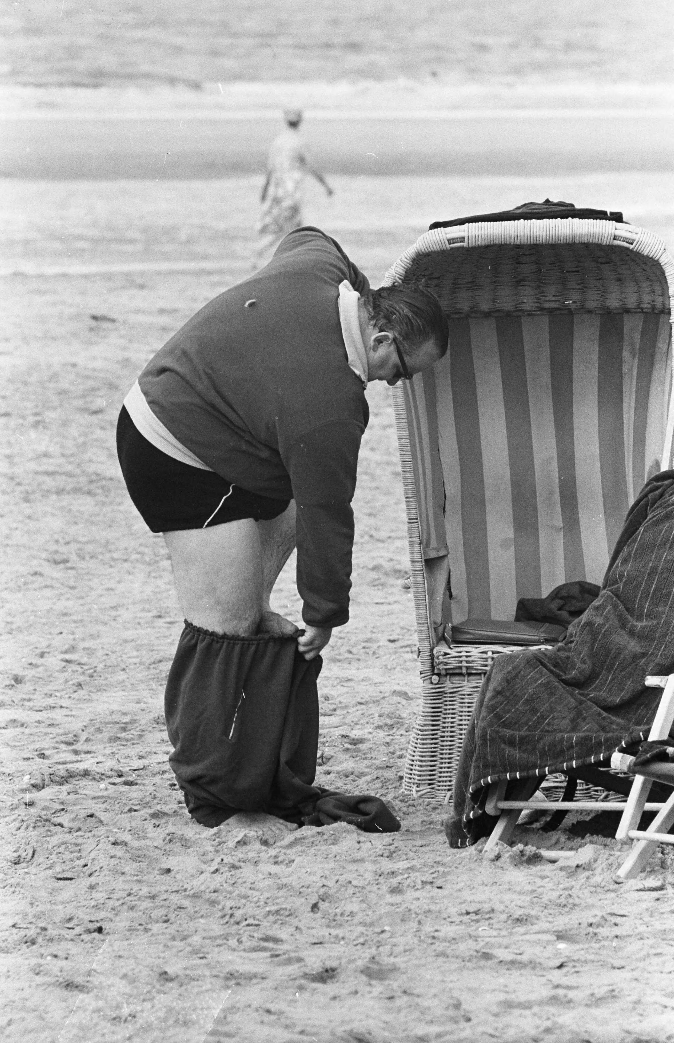 Fotocollectie Anefo — Strand Zandvoort. Corpulente heer probeert zich in broek te wurmen — Foto: Pot, Harry / Anefo. Licentie: Set B: Rechtenvrij / Publiek Domein. Bron: Nationaal Archief. http://hdl.handle.net/10648/aa0b66fe-d0b4-102d-bcf8-003048976d84