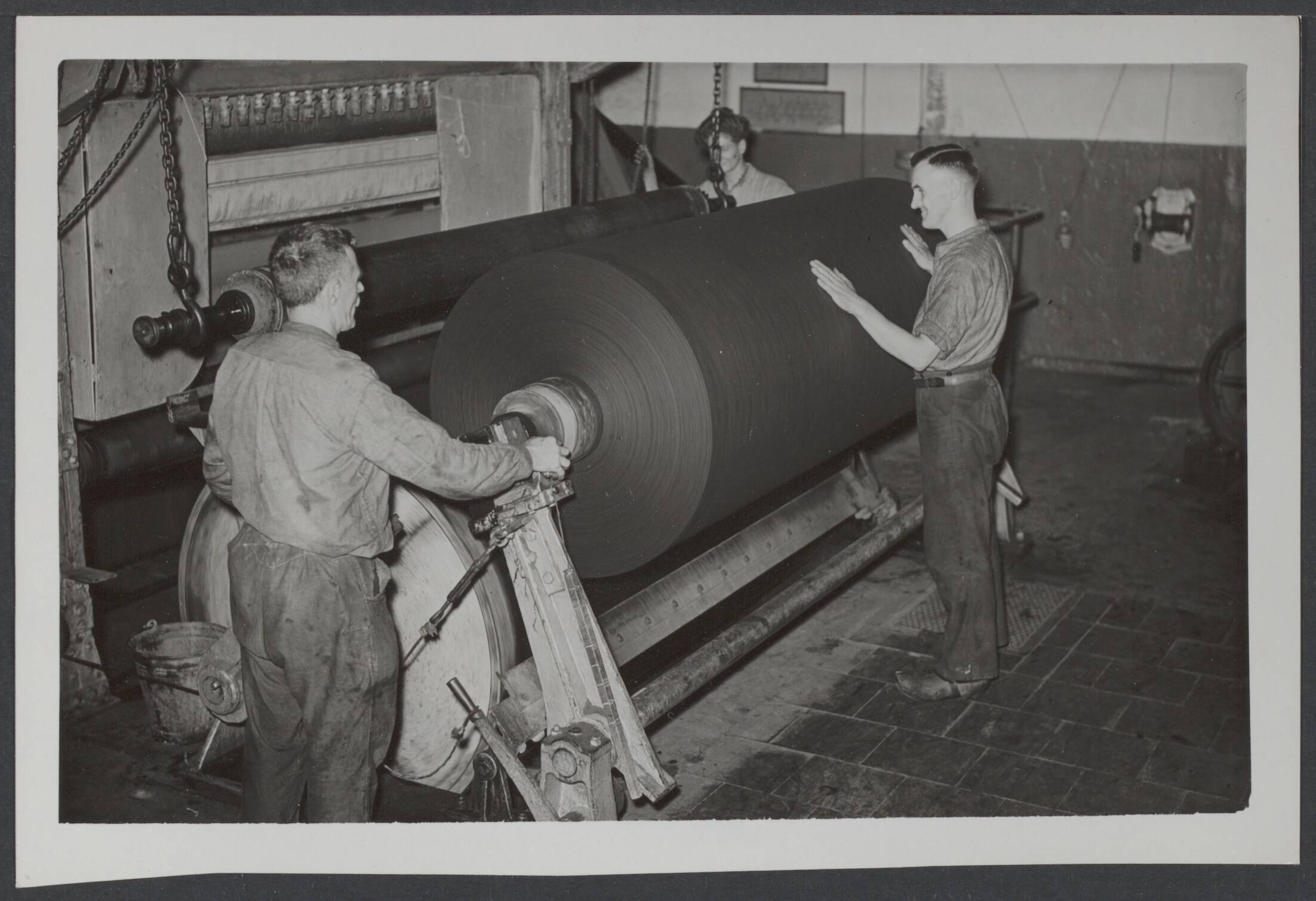 BVD. Bescherming bevolking, enz. Nederland. — Wormer, 29 augustus 1940. Nu de dagen korten en de avond reeds vroeg valt, is de vraag naar verduisteringspapier zeer groot. De machines van een papierfabriek in Wormer werken dag en nacht om aan de behoefte te kunnen voldoen. Het zwarte papier wordt op de "drum" gewikkeld — Foto: N.V. Polygoon. Licentie: Set B: Rechtenvrij / Publiek Domein. Bron: Nationaal Archief. http://hdl.handle.net/10648/d802ad81-1577-cb11-6323-967b25b6c7c4