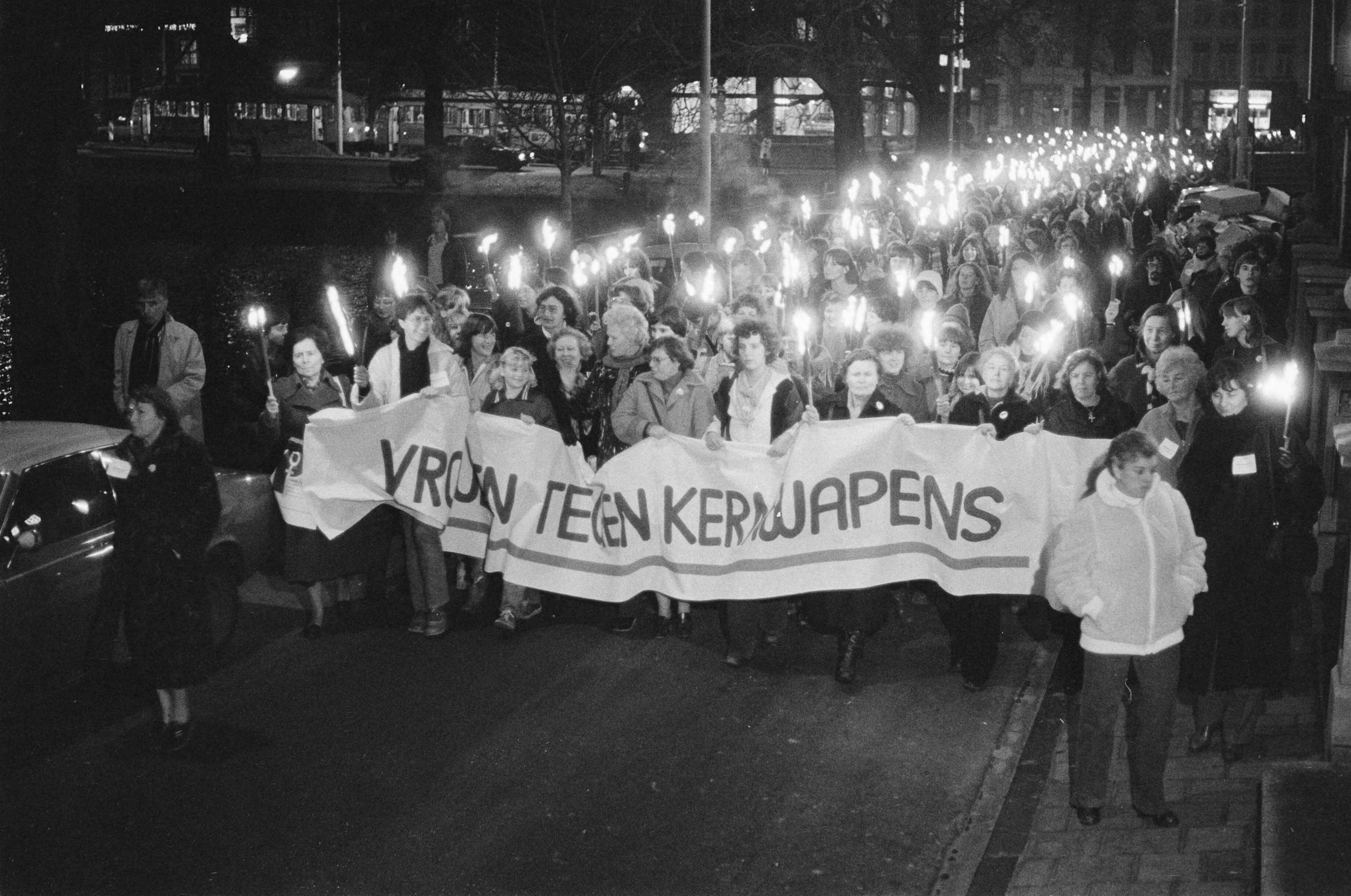 Fotocollectie Anefo — Vrouwen houden een fakkeloptocht in Den Haag tegen de modernisering van kernwapens. Op het spandoek: "Vrouwen tegen kernwapens" — Foto: Croes, Rob C. / Anefo. Licentie: Set B: Rechtenvrij / Publiek Domein. Bron: Nationaal Archief. http://hdl.handle.net/10648/acd616ae-d0b4-102d-bcf8-003048976d84