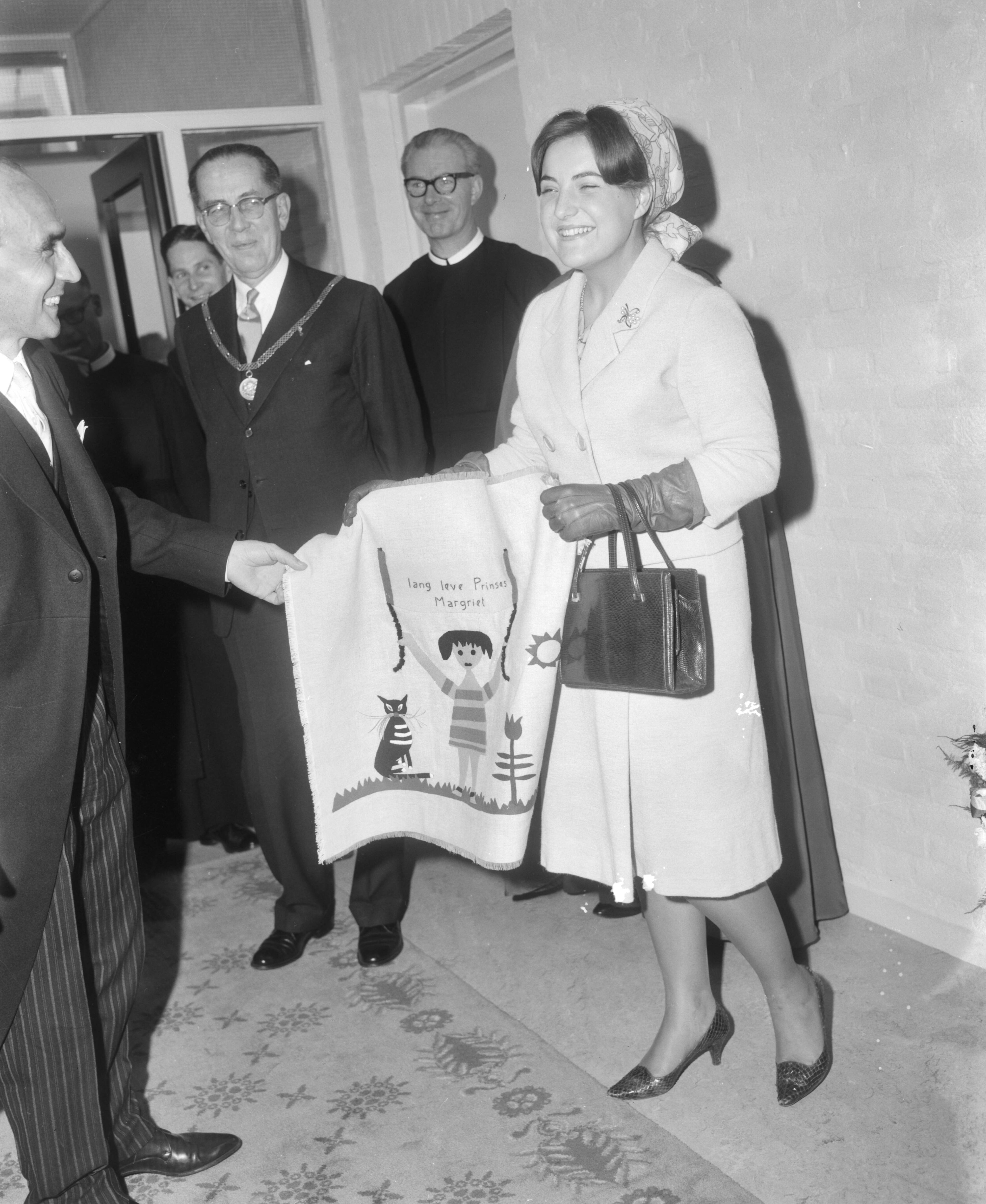 Fotocollectie Anefo — Prinses Margriet heeft in Maastricht de BLO-school Jan Baptist geopend. De prinses met een geborduurde wandlap — Foto: Bilsen, Joop van / Anefo. Licentie: Set B: Rechtenvrij / Publiek Domein. Bron: Nationaal Archief. http://hdl.handle.net/10648/aac42ffe-d0b4-102d-bcf8-003048976d84