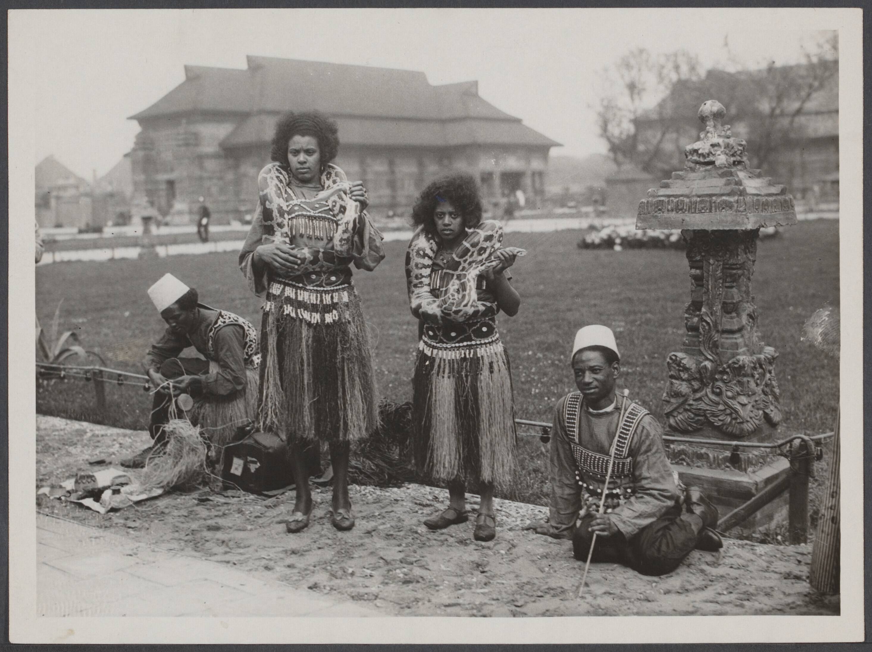 Koloniale tentoonstellingen, Den Haag 1932 - Nederland — Indische Tentoonstelling in het Westbroekpark te Scheveningen [vier "inheemsen". twee van hen hebben slangen om hun nek hangen] — Foto: N.V. Vereenigde Fotobureaux. Licentie: Set B: Rechtenvrij / Publiek Domein. Bron: Nationaal Archief. http://hdl.handle.net/10648/84a06fe5-7ab6-712e-dcbe-98de69a551d3