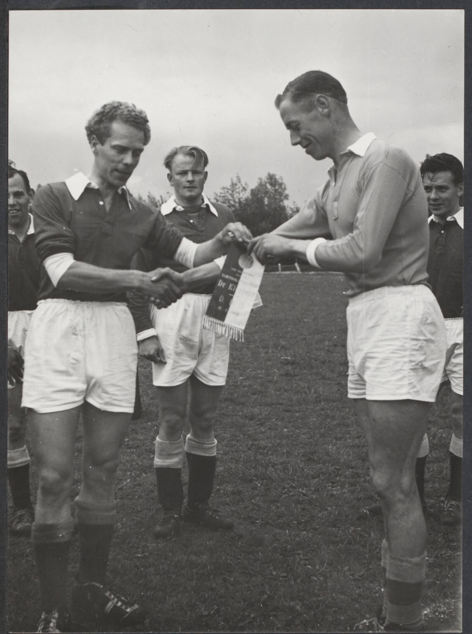 Spaarnestad. Sport en Spel - Nederland — [Serie bedrijfsvoetbal Spaarnestad, diverse jaren] Voetballers Spaarnestad [Serie bedrijfsvoetbal Spaarnestad] [uitwisselen van vaantje voor de wedstrijd, op het vaantje staat "De Kleppers" en "D.D.S." (motto Spaarnestad) en een datum] — Foto: Fotograaf Onbekend / Spaarnestad. Licentie: Set B: Rechtenvrij / Publiek Domein. Bron: Nationaal Archief. http://hdl.handle.net/10648/27acdd03-d781-c566-e829-107f1331e80e
