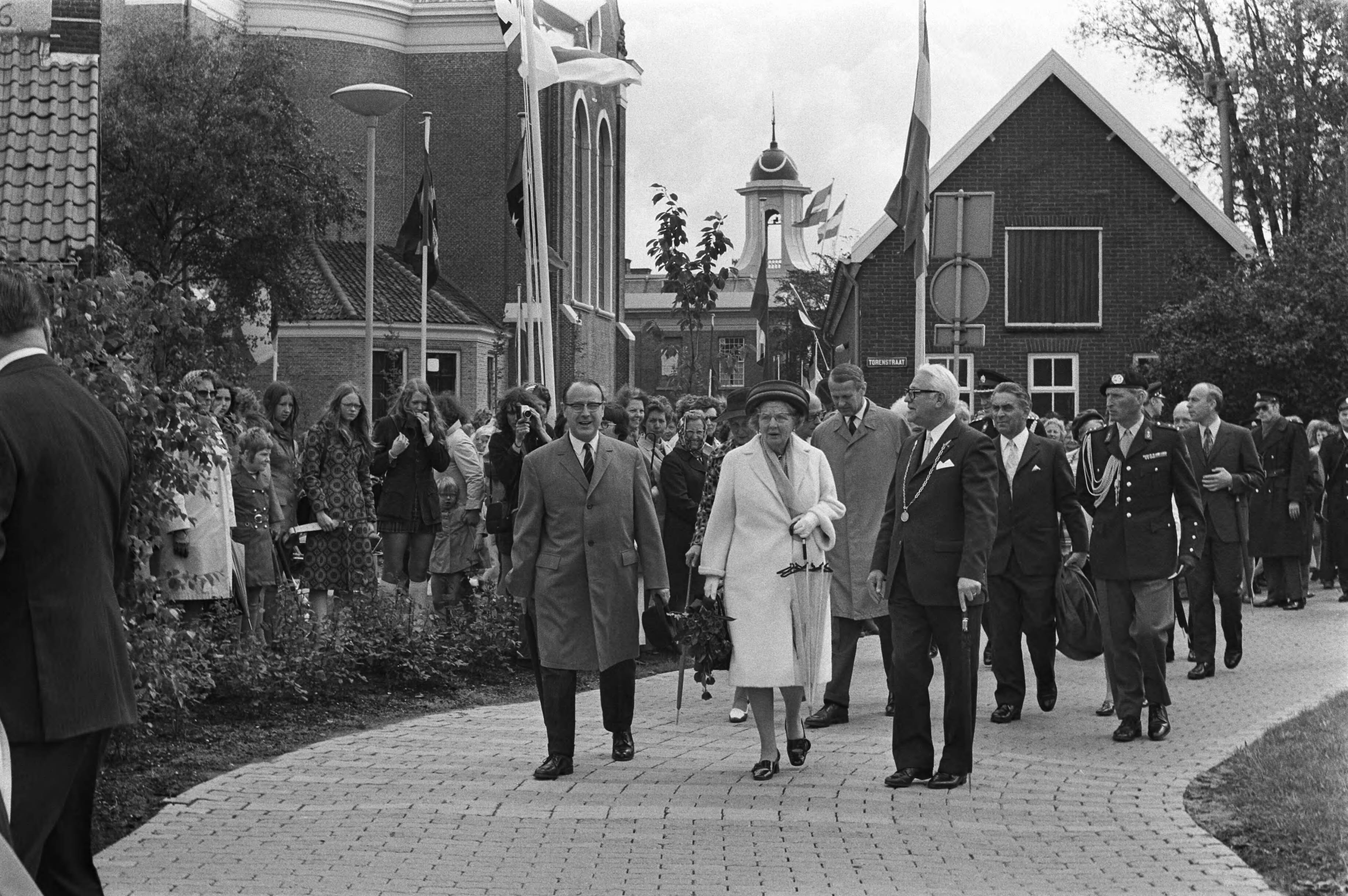 Koningin Juliana op bezoek in de Zaanstreek — Koningin Juliana tijdens de wandeling door Westzaan, in gezelschap van burgemeester van Westzaan, Frederik Verstegen (r.) en de Commissaris der Koningin in Zuid-Holland, mr. F.J. Kranenburg — Foto: Fotograaf Onbekend / Anefo. Licentie: Set B: Rechtenvrij / Publiek Domein. Bron: Nationaal Archief. http://hdl.handle.net/10648/abec10a4-d0b4-102d-bcf8-003048976d84