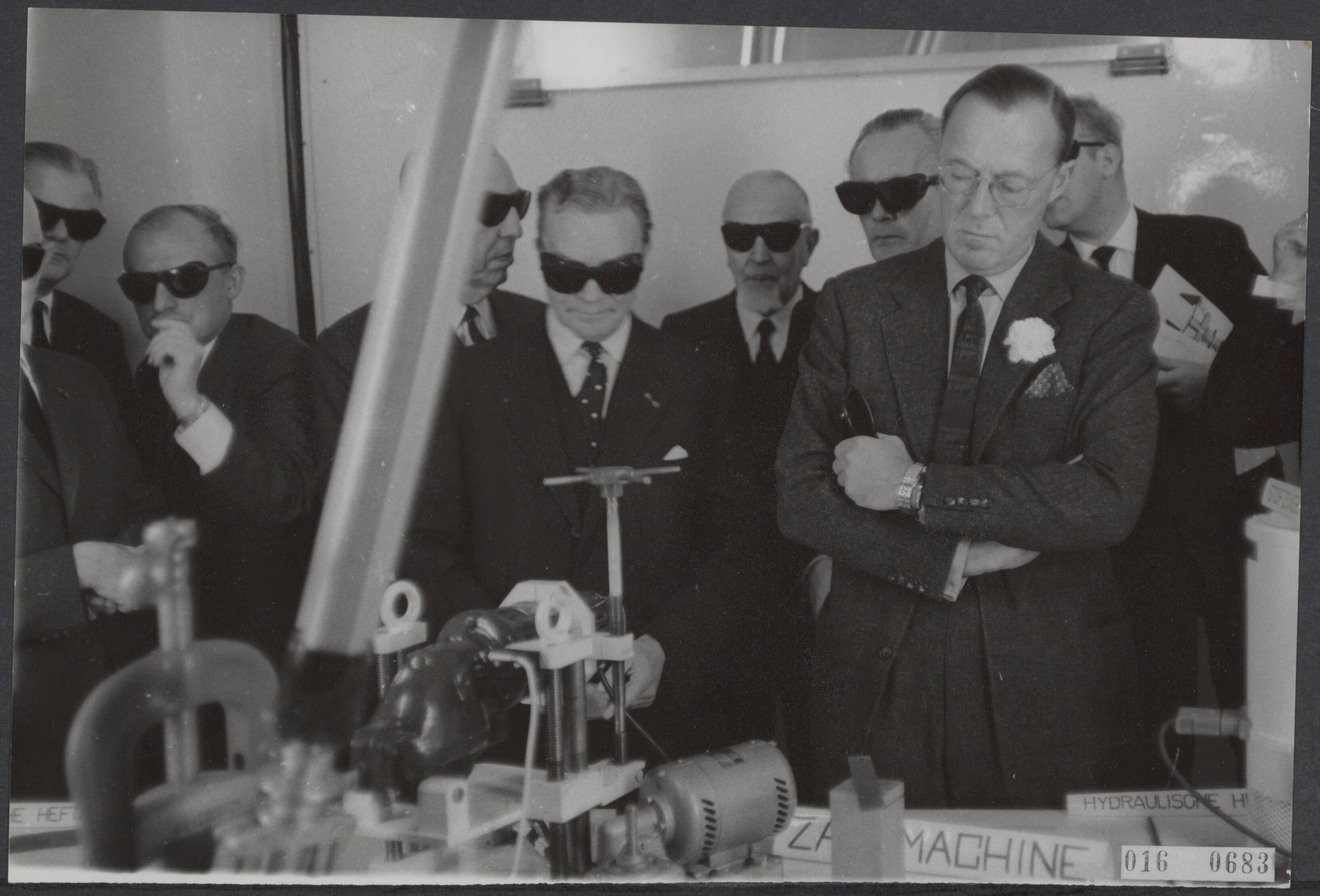 Fotocollectie Elsevier Binnenland — Officiële opening van het laboratorium voor sterk-radioactieve opbjecten in het Reactor Centrum te Petten door Prins Bernhard. Zonder zwarte bril staat de prins in een betonnen ruimte waarin zeer fel oranje licht de machines op afstand worden bediend — Foto: Nijs, Jac. de / Anefo. Licentie: Set B: Rechtenvrij / Publiek Domein. Bron: Nationaal Archief. http://hdl.handle.net/10648/adba1e94-d0b4-102d-bcf8-003048976d84