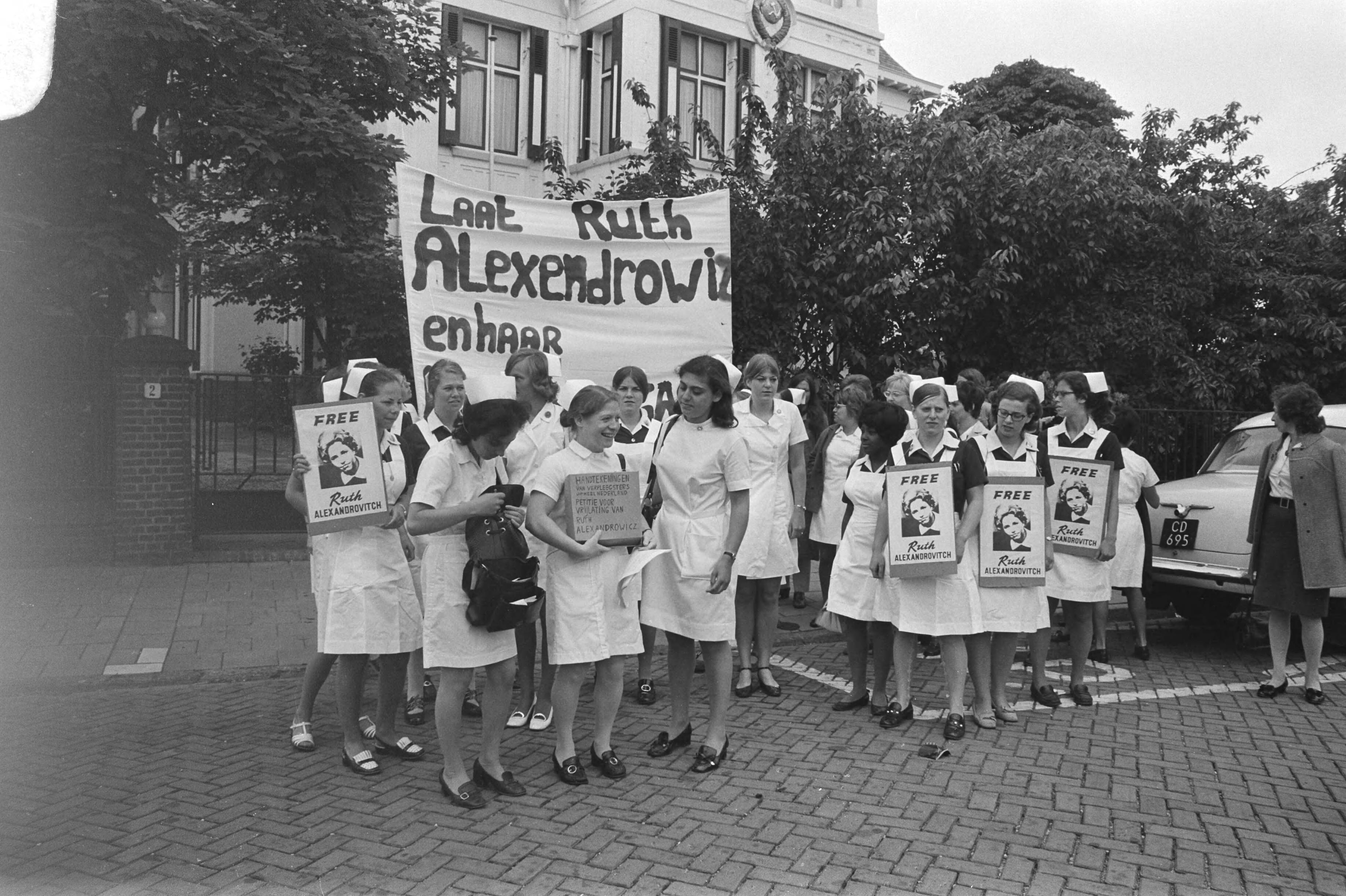 Verpleegsters demonstreren voor Russische ambassade in Den Haag tegen gevangenschap van Ruth Alexandrovitch — Verpleegsters met een spandoek voor de ambassade in Den Haag — Foto: Fotograaf Onbekend / Anefo. Licentie: Set B: Rechtenvrij / Publiek Domein. Bron: Nationaal Archief. http://hdl.handle.net/10648/abc2516a-d0b4-102d-bcf8-003048976d84