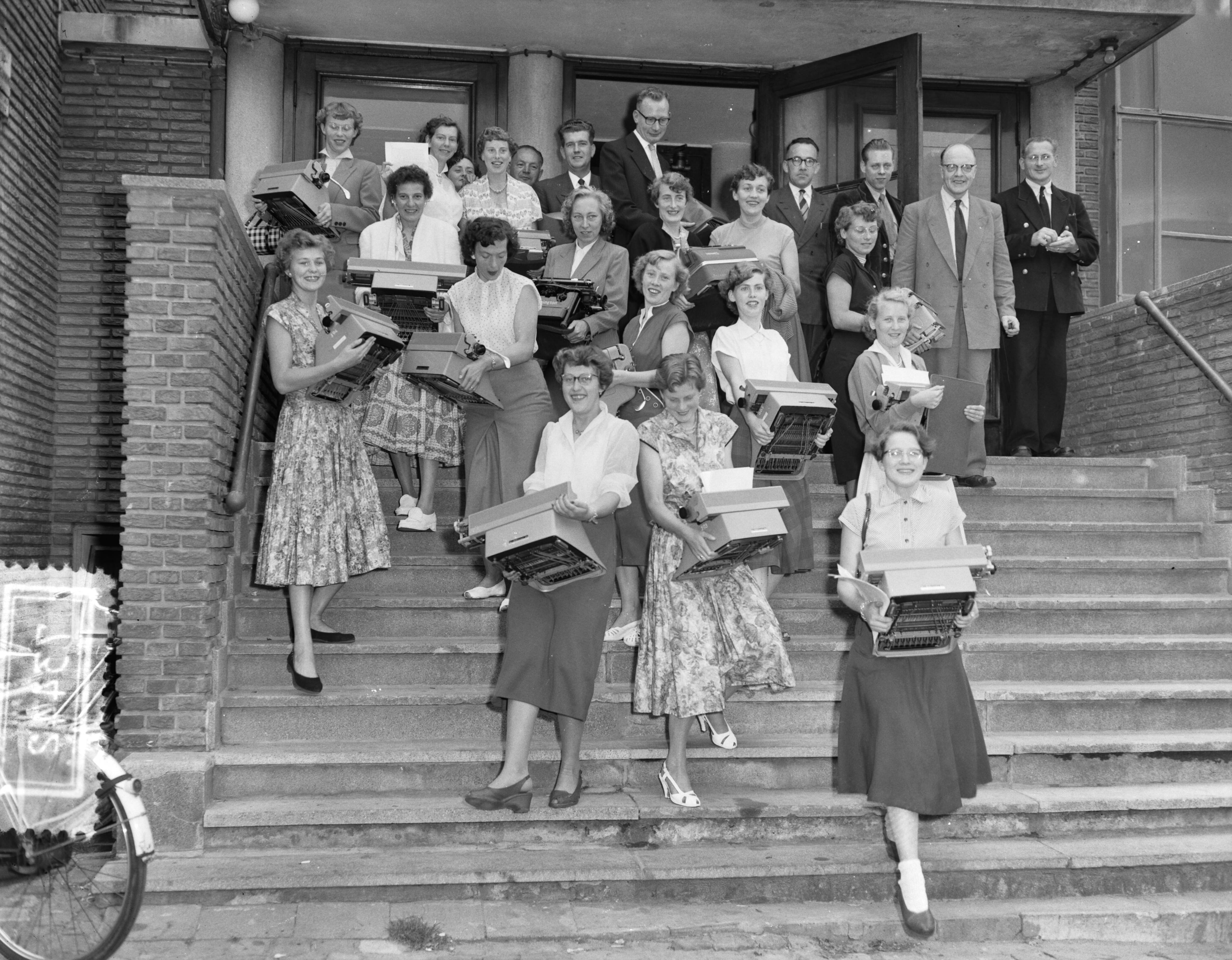 Fotocollectie Anefo — Kampioenschap typen in Den Haag. Aankomst deelnemers met hun schrijfmachines — Foto: Pot, Harry / Anefo. Licentie: Set B: Rechtenvrij / Publiek Domein. Bron: Nationaal Archief. http://hdl.handle.net/10648/a93b7688-d0b4-102d-bcf8-003048976d84