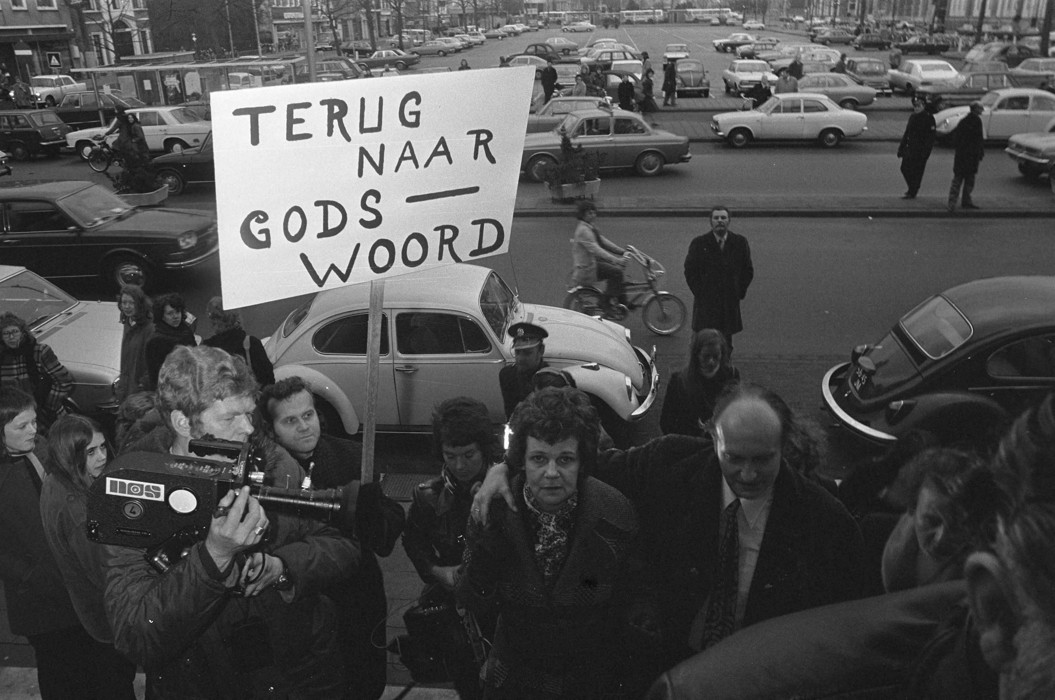 Fotocollectie Anefo — Euthanasie-proces begonnen tegen mw Postma van Boven in Leeuwarden, echtpaar Postma en demonstrant met protestbord — Foto: Verhoeff, Bert / Anefo. Licentie: Set B: Rechtenvrij / Publiek Domein. Bron: Nationaal Archief. http://hdl.handle.net/10648/ac246ddc-d0b4-102d-bcf8-003048976d84