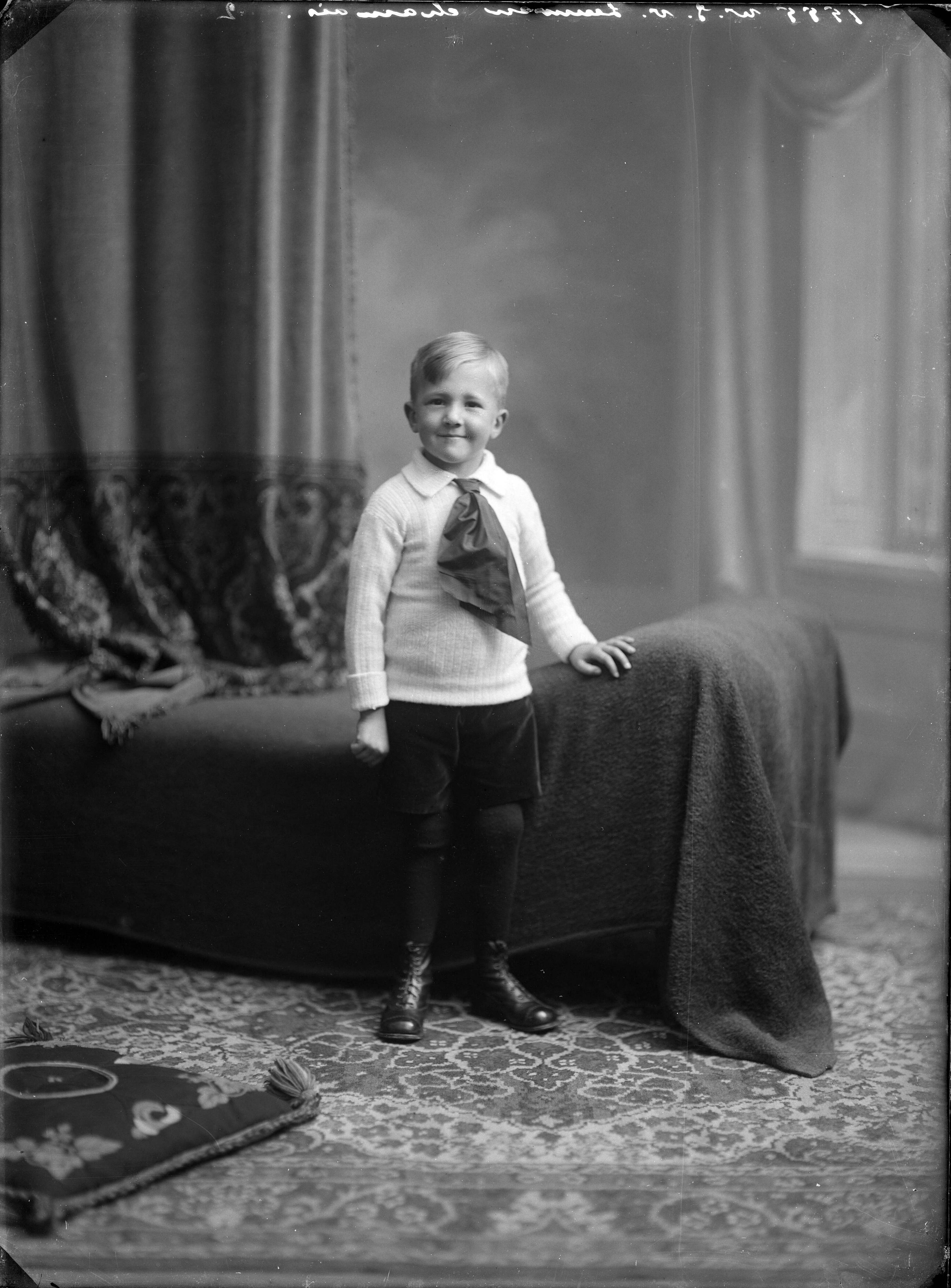 Berg, van den (BERG 050) — Studio-opnames. Een jongetje van ca. 8 jaar met witte trui en grote stropdasstrik voor een bank met drapeersels. Haarlem, Nederland. 1918-1930.1555 W.J. v. Leeuwen chamois 2 — Foto: Berg, Th.C.J. van den / Spaarnestad Photo (05887). Licentie: Set B: Rechtenvrij / Publiek Domein. Bron: Nationaal Archief. http://hdl.handle.net/10648/35429da7-c5c0-a382-e063-6df0900a6686