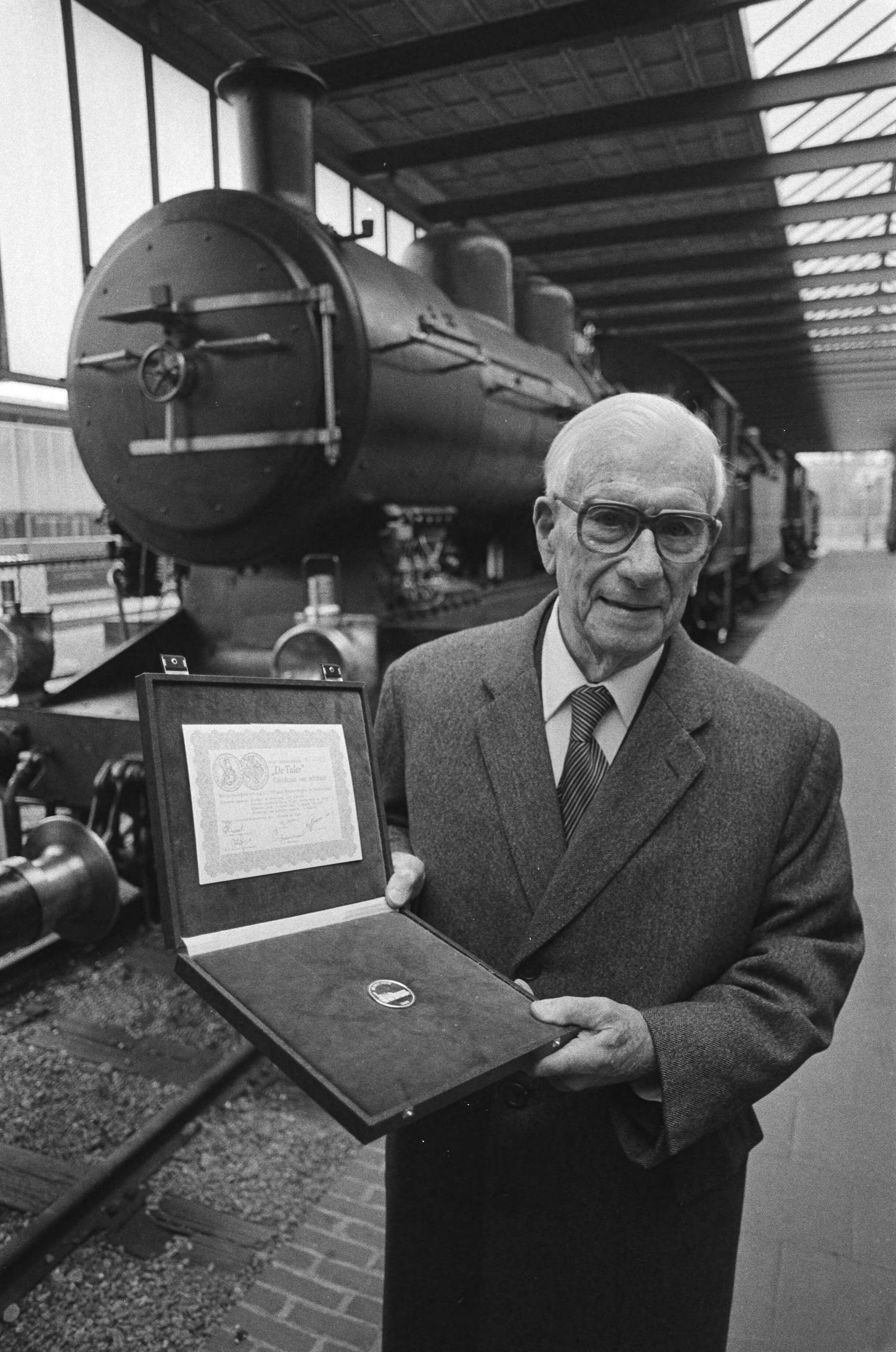 Fotocollectie Anefo — Dr. ir. F. Q. Den Hollander (oud-president NS) (r.) krijgt in het Spoorwegmuseum in Utrecht 1ste exemplaar serie US-herdenkingsmunten door E. M. Meupelerberg / — Foto: Antonisse, Marcel / Anefo. Licentie: Set B: Rechtenvrij / Publiek Domein. Bron: Nationaal Archief. http://hdl.handle.net/10648/ad102448-d0b4-102d-bcf8-003048976d84