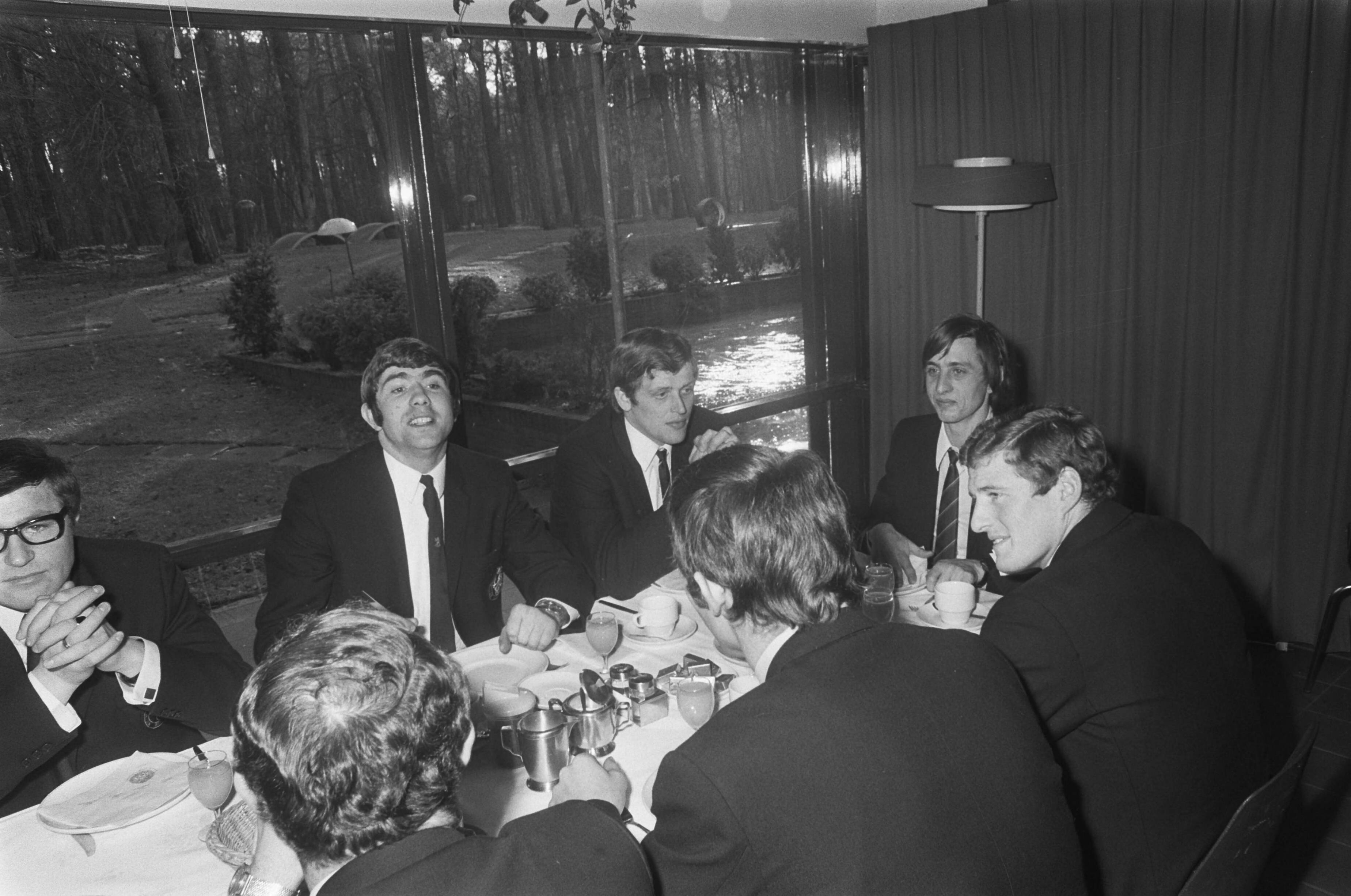 Fotocollectie Anefo — Nederlands elftal, dat tegen Engeland zal spelen in KNVB-sportcentrum te Zeist. Spelers aan lunch. Vlnr. Rinus Israël, Hans Eijkenbroek, Piet Keizer, Johan Cruijff, Wim Jansen. Op de rug gezien Willem van Hanegem — Foto: Mieremet, Rob / Anefo. Licentie: Set B: Rechtenvrij / Publiek Domein. Bron: Nationaal Archief. http://hdl.handle.net/10648/ab88a956-d0b4-102d-bcf8-003048976d84