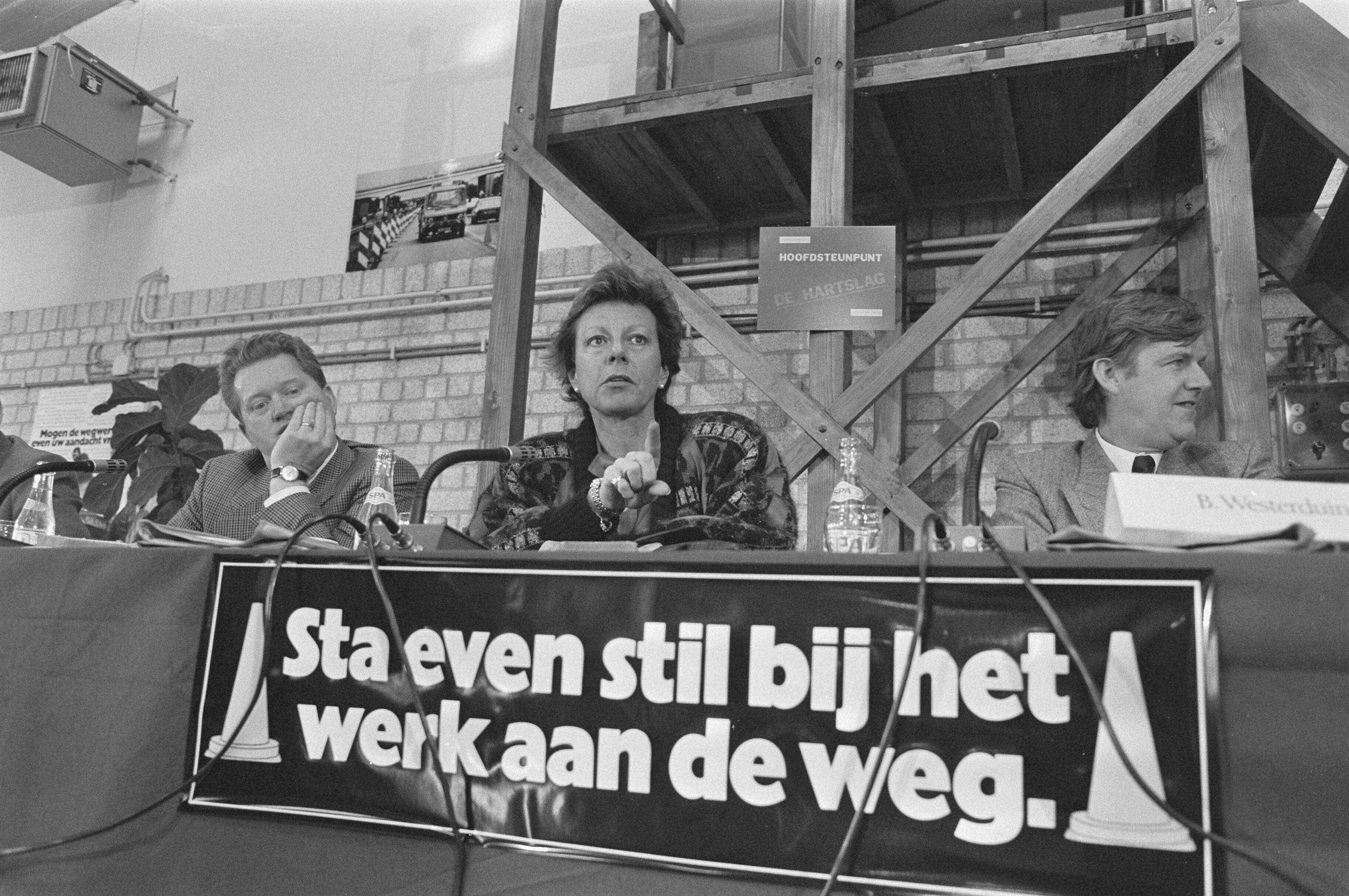 Minister Kroes van Verkeer en Waterstaat stelt langs de A12 de nieuwste mobiele rijstrook signalering in werking — Kroes, Neelie|Reeuwijk|Zuid-Holland|straatmeubilair |wegwerkzaamheden |ministers |verkeer — Foto: Croes, Rob C. / Anefo. Licentie: Set B: Rechtenvrij / Publiek Domein. Bron: Nationaal Archief. http://hdl.handle.net/10648/ad522276-d0b4-102d-bcf8-003048976d84