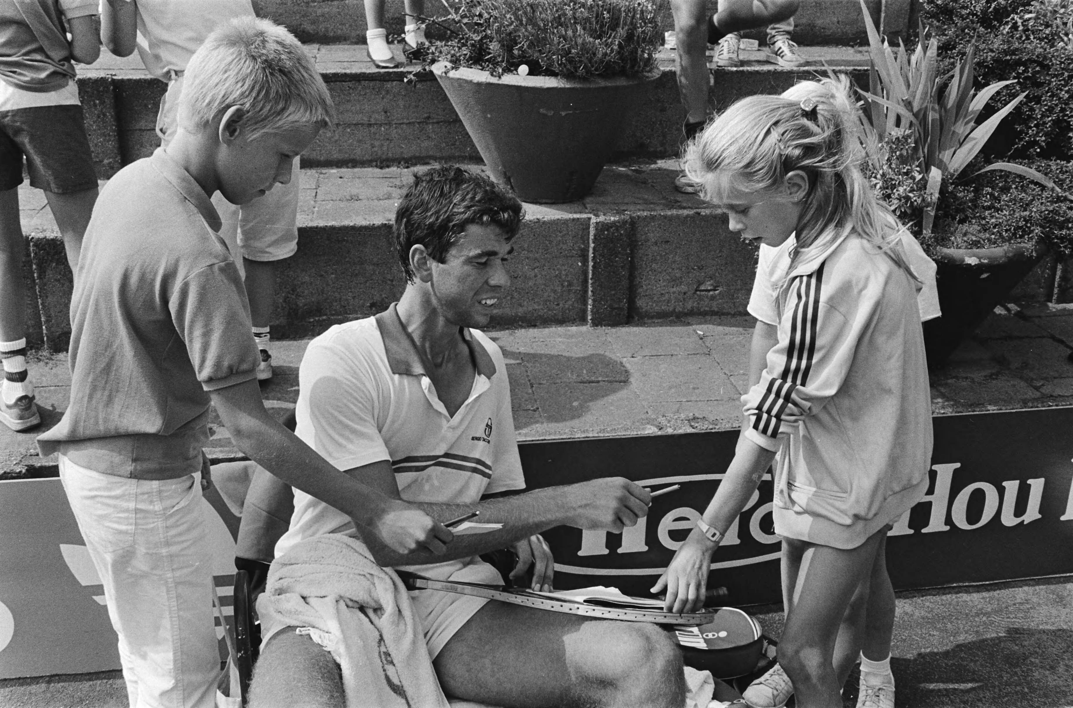 Nederlands Kampioenschap Tennis op de METS-banen in Scheveningen — Michiel Schapers deelt handtekeningen uit — Foto: Antonisse, Marcel / Anefo. Licentie: Set B: Rechtenvrij / Publiek Domein. Bron: Nationaal Archief. http://hdl.handle.net/10648/ad2c4ee8-d0b4-102d-bcf8-003048976d84