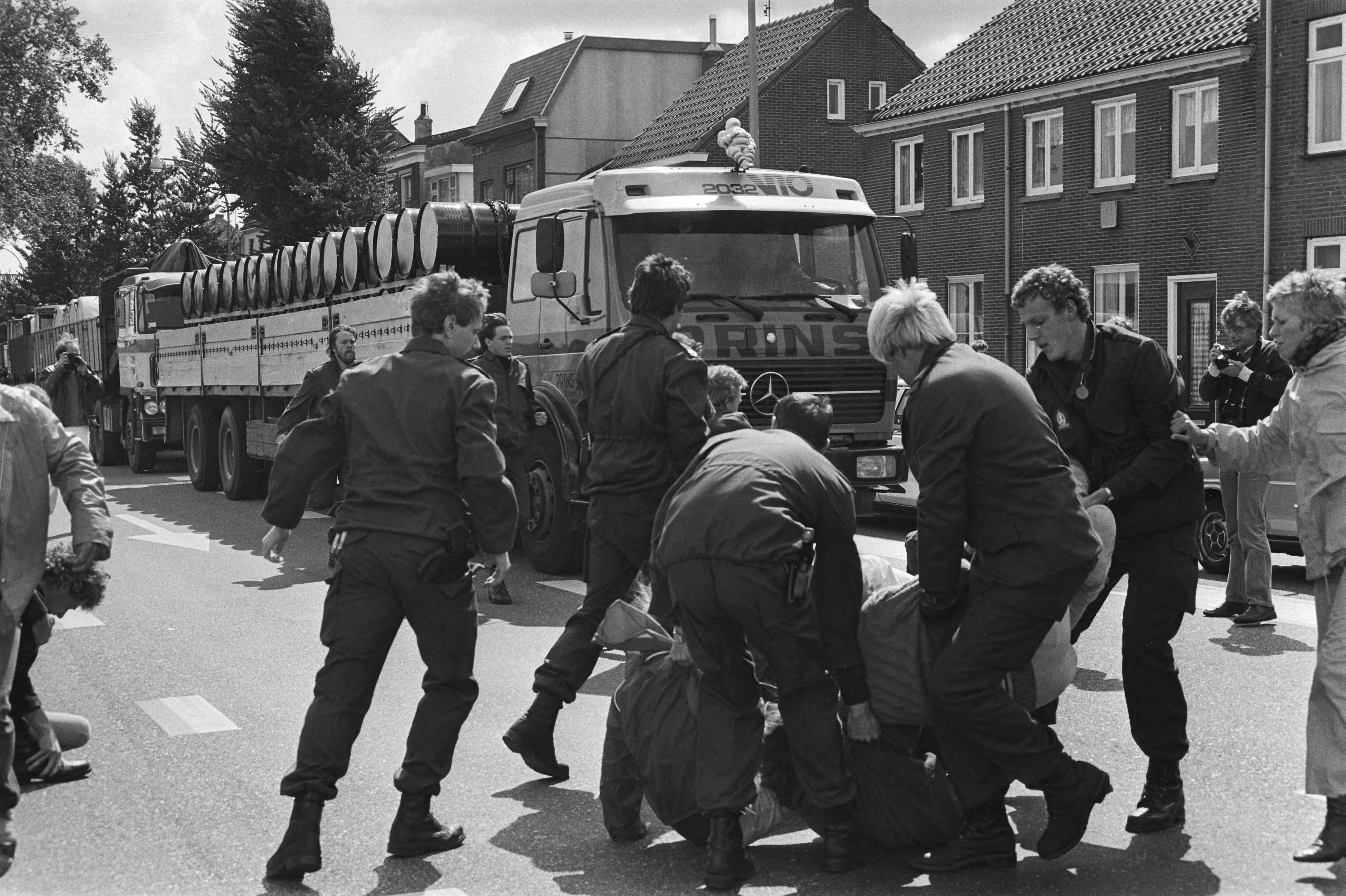 Fotocollectie Anefo — Akties tegen transport radioactief afval van Petten naar Den Helder ; aktievoerders worden verwijderd door ME, wagens met afval — Foto: Dijk, Hans van / Anefo. Licentie: Set B: Rechtenvrij / Publiek Domein. Bron: Nationaal Archief. http://hdl.handle.net/10648/ad1ce6a6-d0b4-102d-bcf8-003048976d84