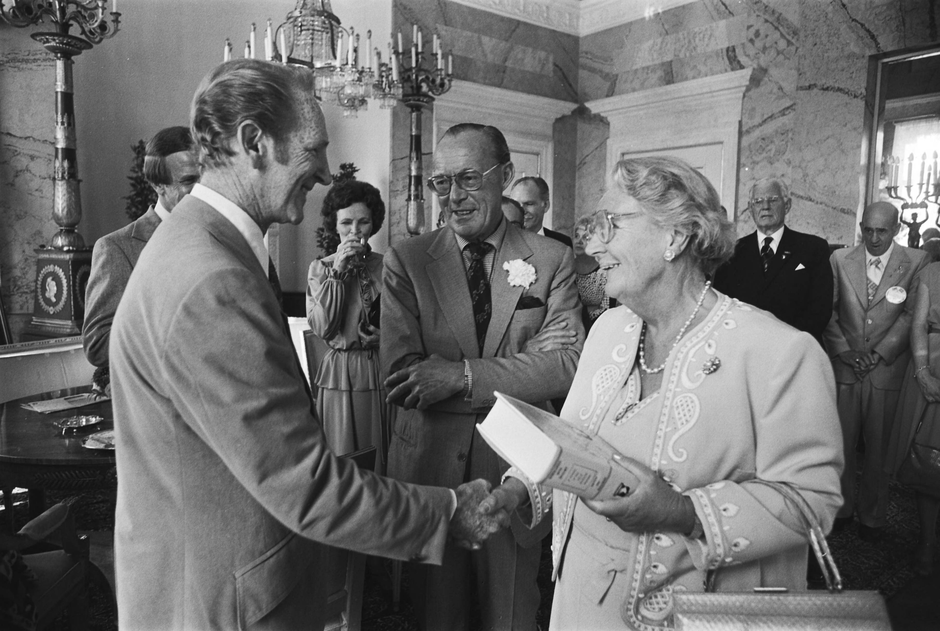 Boek over de 101e Airborne Division door oudstrijders aan koningin Juliana aangeboden op Paleis Soestdijk — De president van de 101st Airborne Division Association, Weldon Combs, overhandigt een boek over deze divisie aan koningin Juliana, terwijl prins Bernhard toekijkt — Foto: Suyk, Koen / Anefo. Licentie: Set B: Rechtenvrij / Publiek Domein. Bron: Nationaal Archief. http://hdl.handle.net/10648/acd14ee4-d0b4-102d-bcf8-003048976d84