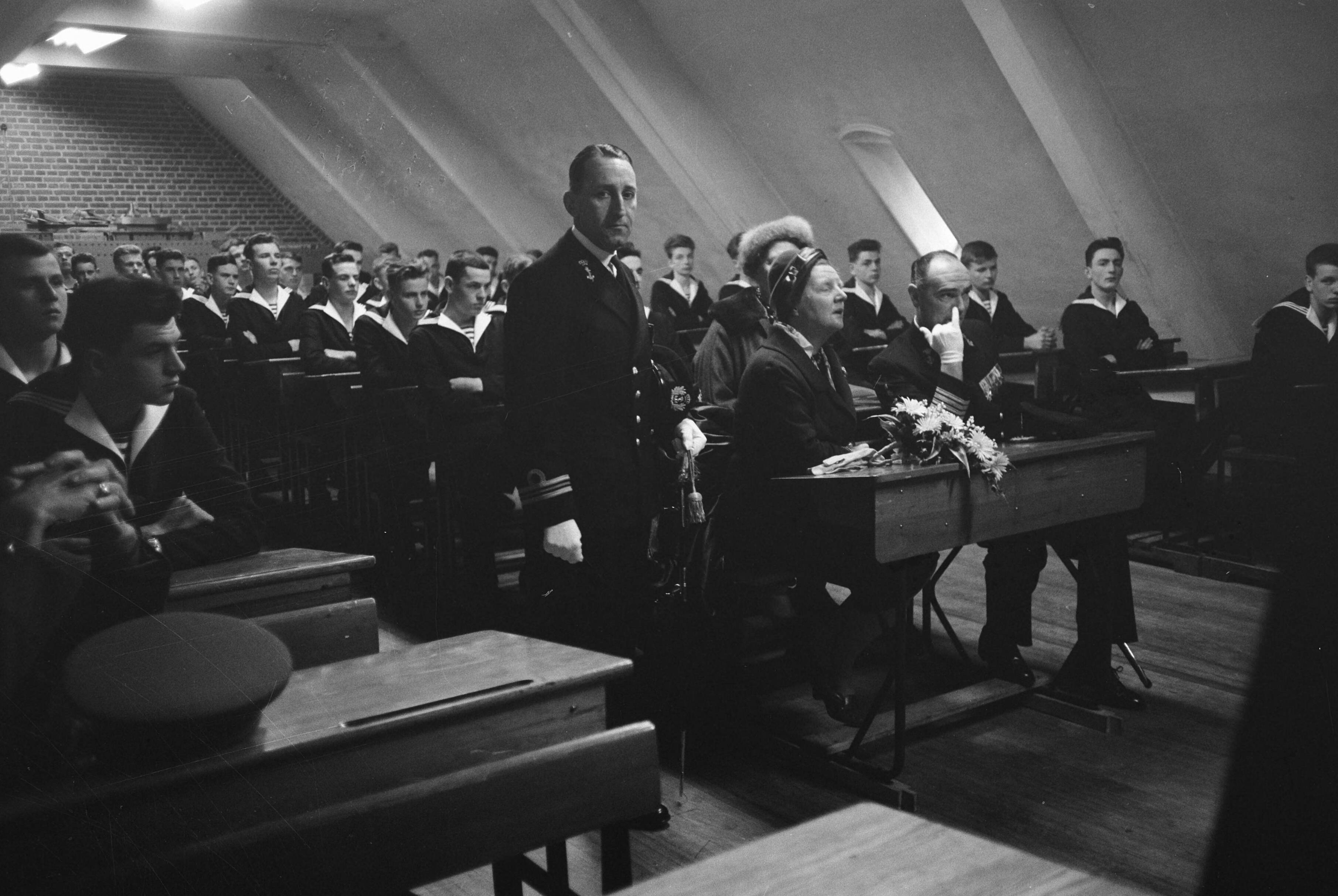 Fotocollectie Anefo — Koningin Juliana bezoekt marinekamp Loosdrecht. De koningin volgt een les over het verkeer in een schoolbank met rechts naast haar de commandant van het opleidingscentrum kapitein-ter-zee H.J. Baay — Foto: Pot, Harry / Anefo. Licentie: Set B: Rechtenvrij / Publiek Domein. Bron: Nationaal Archief. http://hdl.handle.net/10648/a9ce3842-d0b4-102d-bcf8-003048976d84