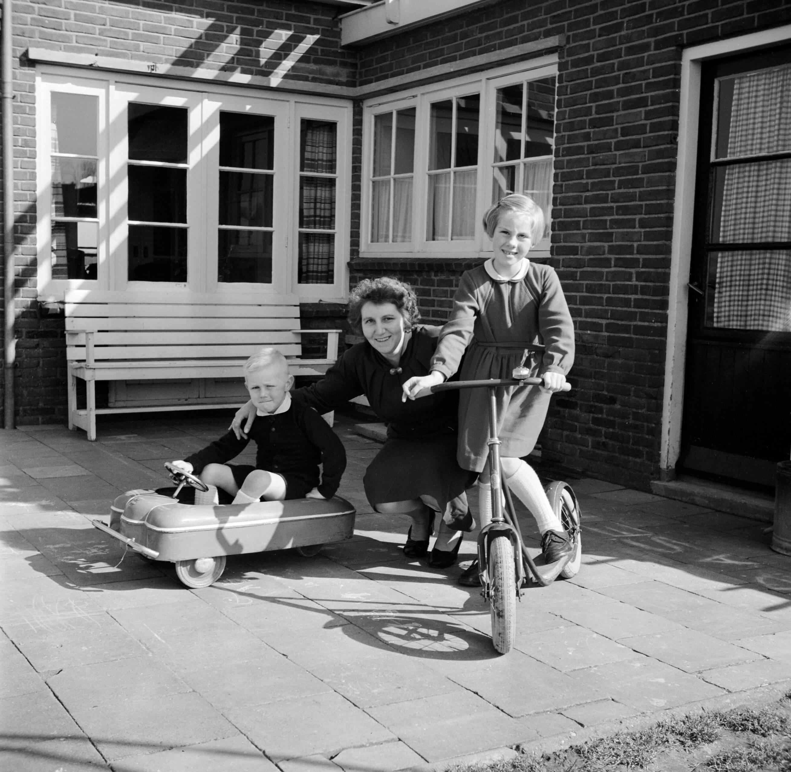 Fotocollectie Van de Poll — De echtgenote van Gerard de Jong met vierjarige zoon Gerrie en achtjarige dochter Marietje op een plaatsje bij hun huis — Foto: Poll, Willem van de. Licentie: Set B: Rechtenvrij / Publiek Domein. Bron: Nationaal Archief. http://hdl.handle.net/10648/aecccad4-d0b4-102d-bcf8-003048976d84