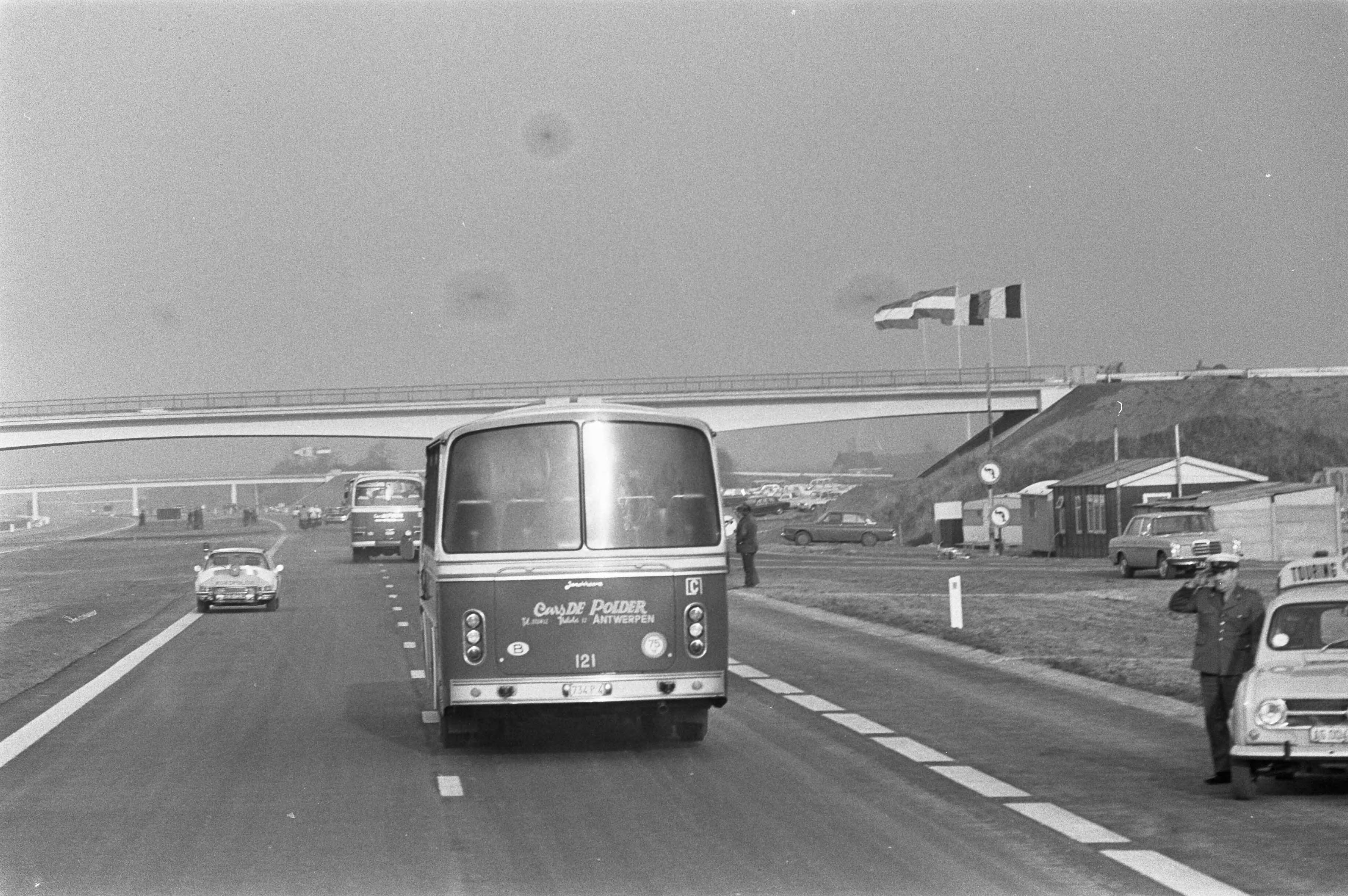 Opening van de E10, de nieuwe snelweg tussen Breda en Antwerpen, door — De bus met daarin koningin Juliana en koning Boudewijn op de nieuwe weg — Foto: Fotograaf Onbekend / Anefo. Licentie: Set B: Rechtenvrij / Publiek Domein. Bron: Nationaal Archief. http://hdl.handle.net/10648/abde612a-d0b4-102d-bcf8-003048976d84