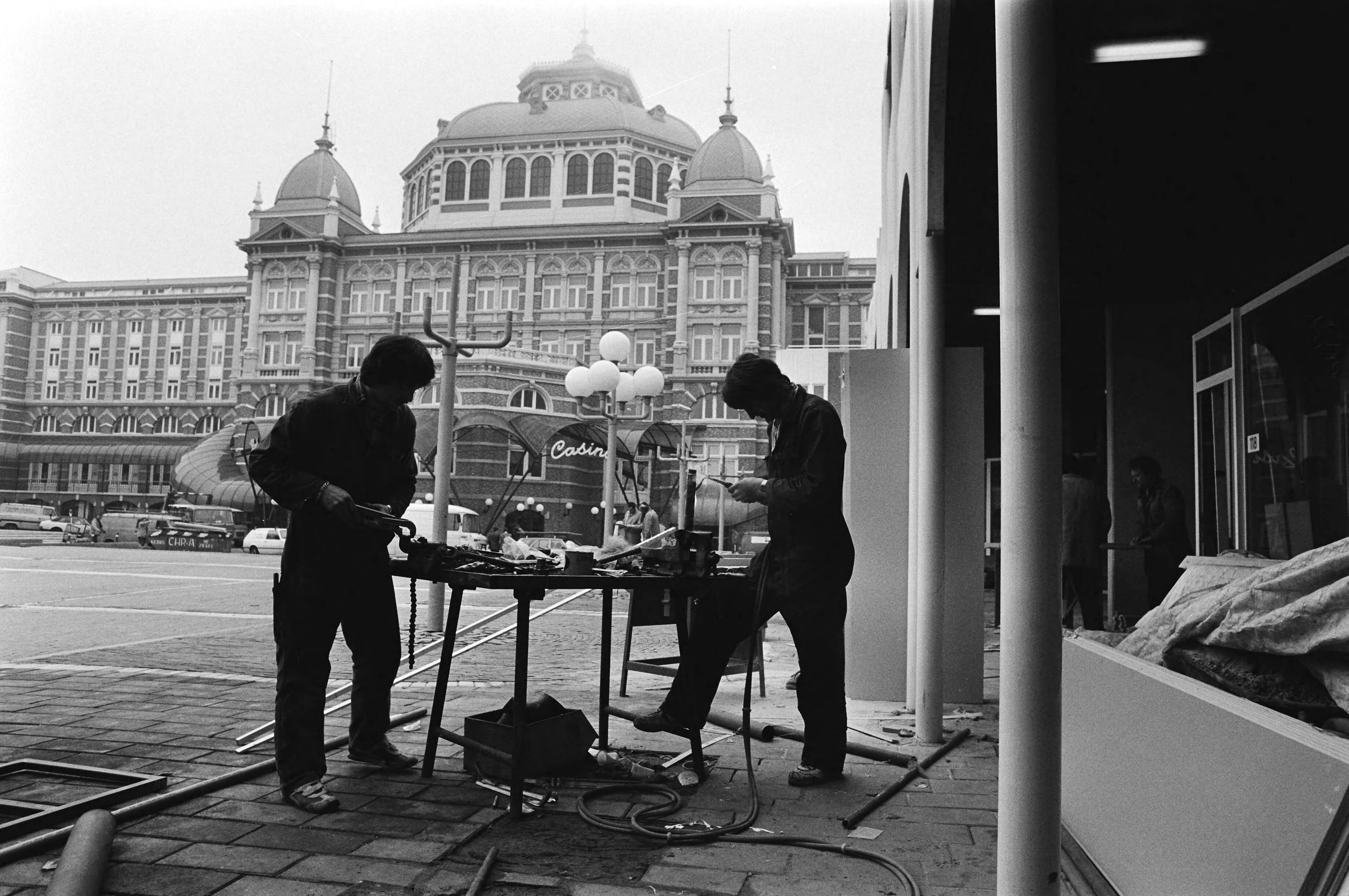 Fotocollectie Anefo — Heropening van het vernieuwde Gevers Deynootplein (bij Kurhaus) in Scheveningen, twee werklui aan het werk bij het plein — Foto: Antonisse, Marcel / Anefo. Licentie: Set B: Rechtenvrij / Publiek Domein. Bron: Nationaal Archief. http://hdl.handle.net/10648/acf8a386-d0b4-102d-bcf8-003048976d84