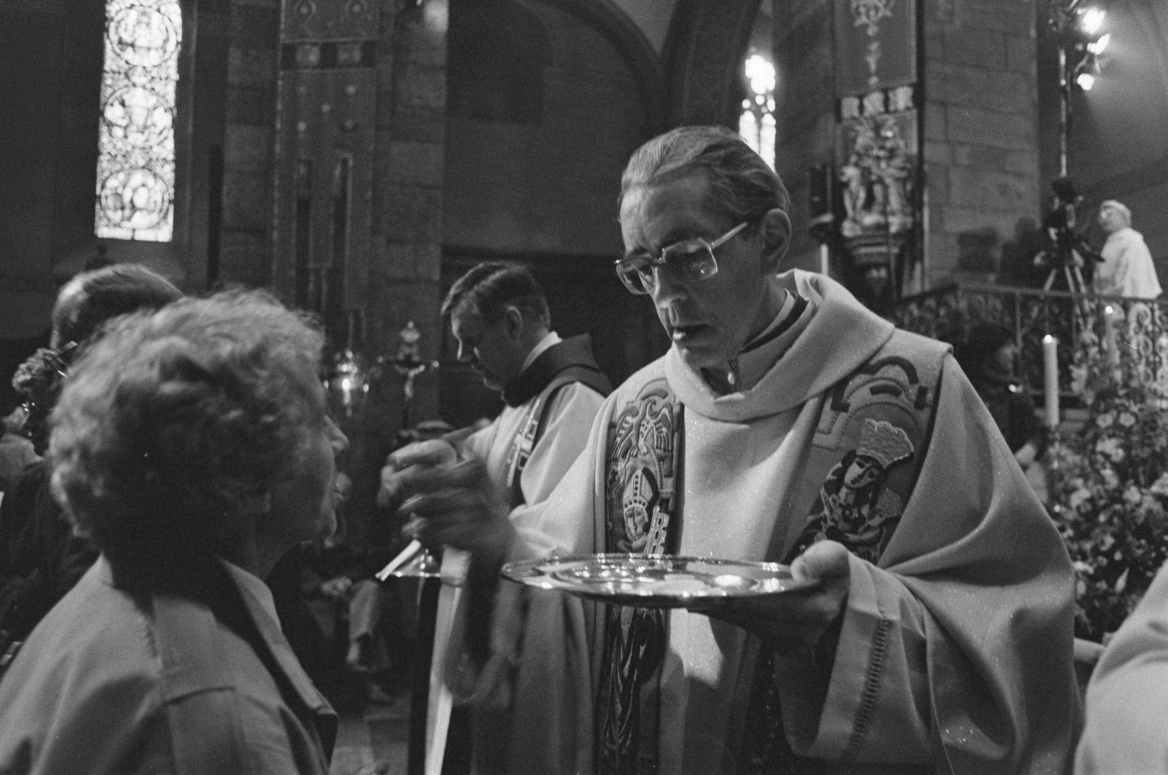 Fotocollectie Anefo — Gebedsdienst Paus J. P. II op groot projectiescherm voor Onze Lieve Vrouwebasiliek in Maastricht; bisschop Gijsen deelt hosties uit. — Foto: Gerrits, Roland / Anefo. Licentie: Set B: Rechtenvrij / Publiek Domein. Bron: Nationaal Archief. http://hdl.handle.net/10648/ad614486-d0b4-102d-bcf8-003048976d84