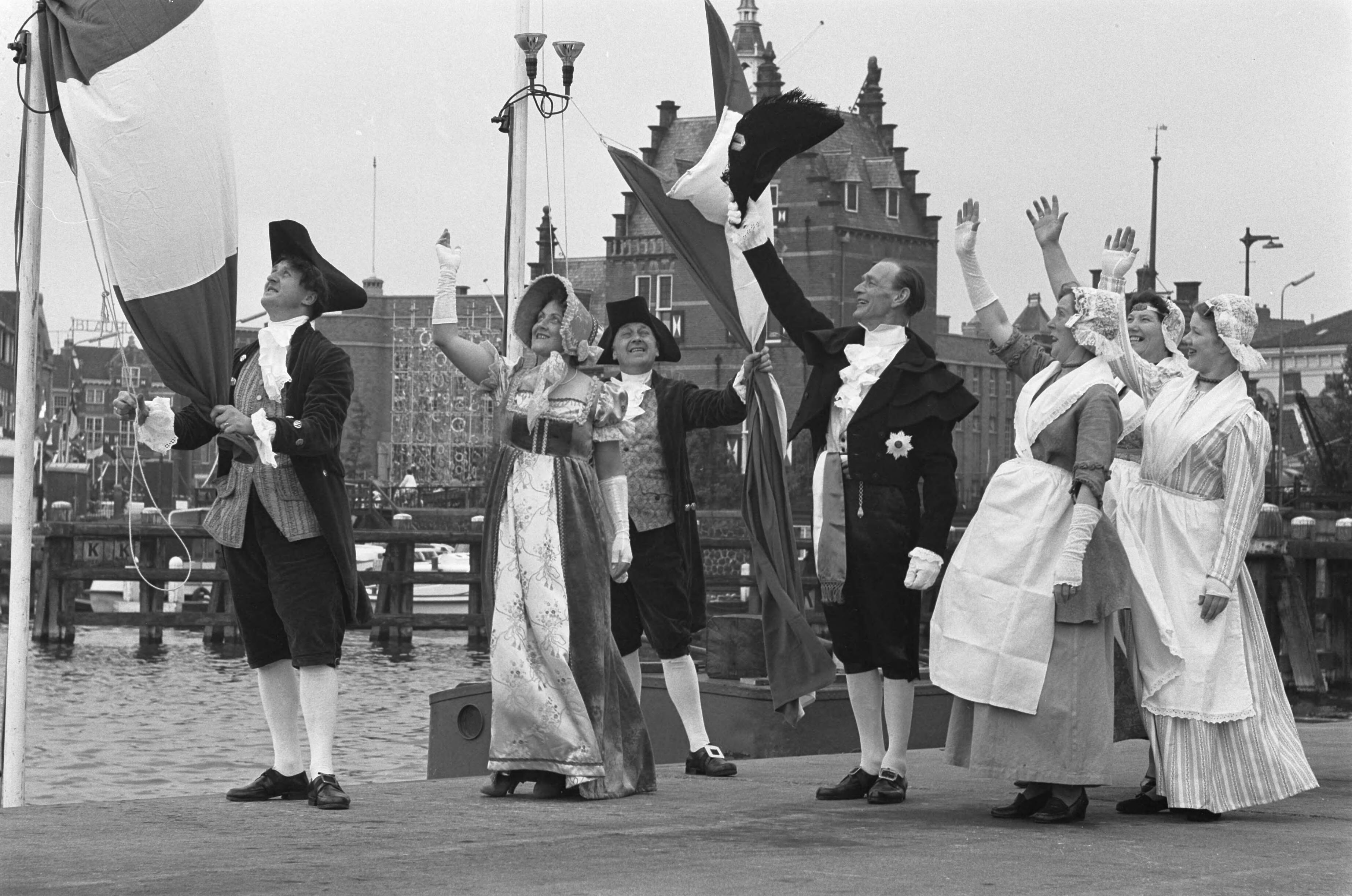 Fotocollectie Anefo — Zaandam 150 jaar stad. Zaandammers in historische kostuums. Vlaggen worden opgehesen — Foto: Pot, Harry / Anefo. Licentie: Set B: Rechtenvrij / Publiek Domein. Bron: Nationaal Archief. http://hdl.handle.net/10648/a9d8566a-d0b4-102d-bcf8-003048976d84