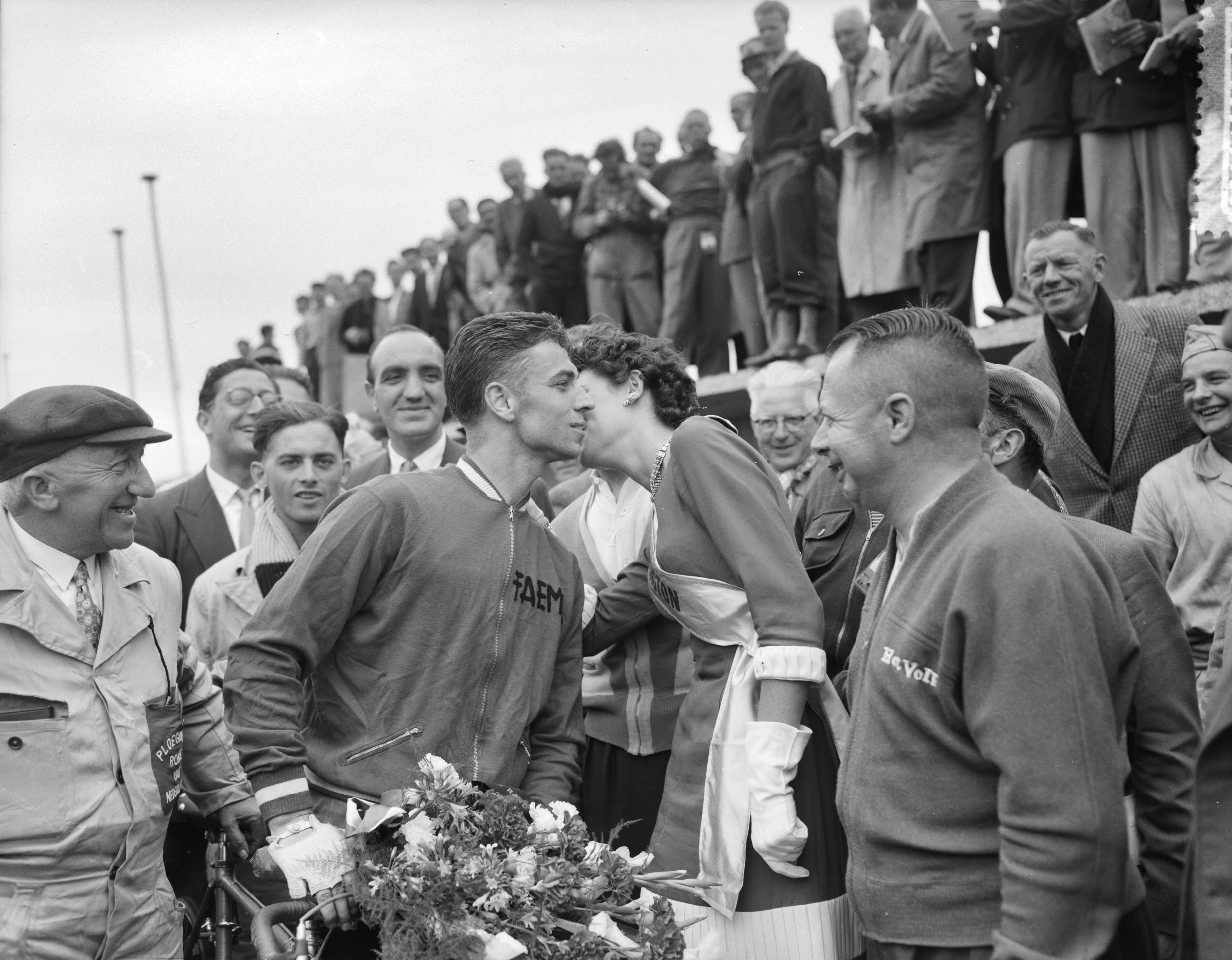 Fotocollectie Anefo — Ronde van Nederland. 3e etappe Leeuwarden-Zandvoort. Rik Van Looy winnaar derde etappe. Kus van Miss Remington na huldiging op het circuit van Zandvoort — Foto: Bilsen, Joop van / Anefo. Licentie: Set B: Rechtenvrij / Publiek Domein. Bron: Nationaal Archief. http://hdl.handle.net/10648/a94d0542-d0b4-102d-bcf8-003048976d84