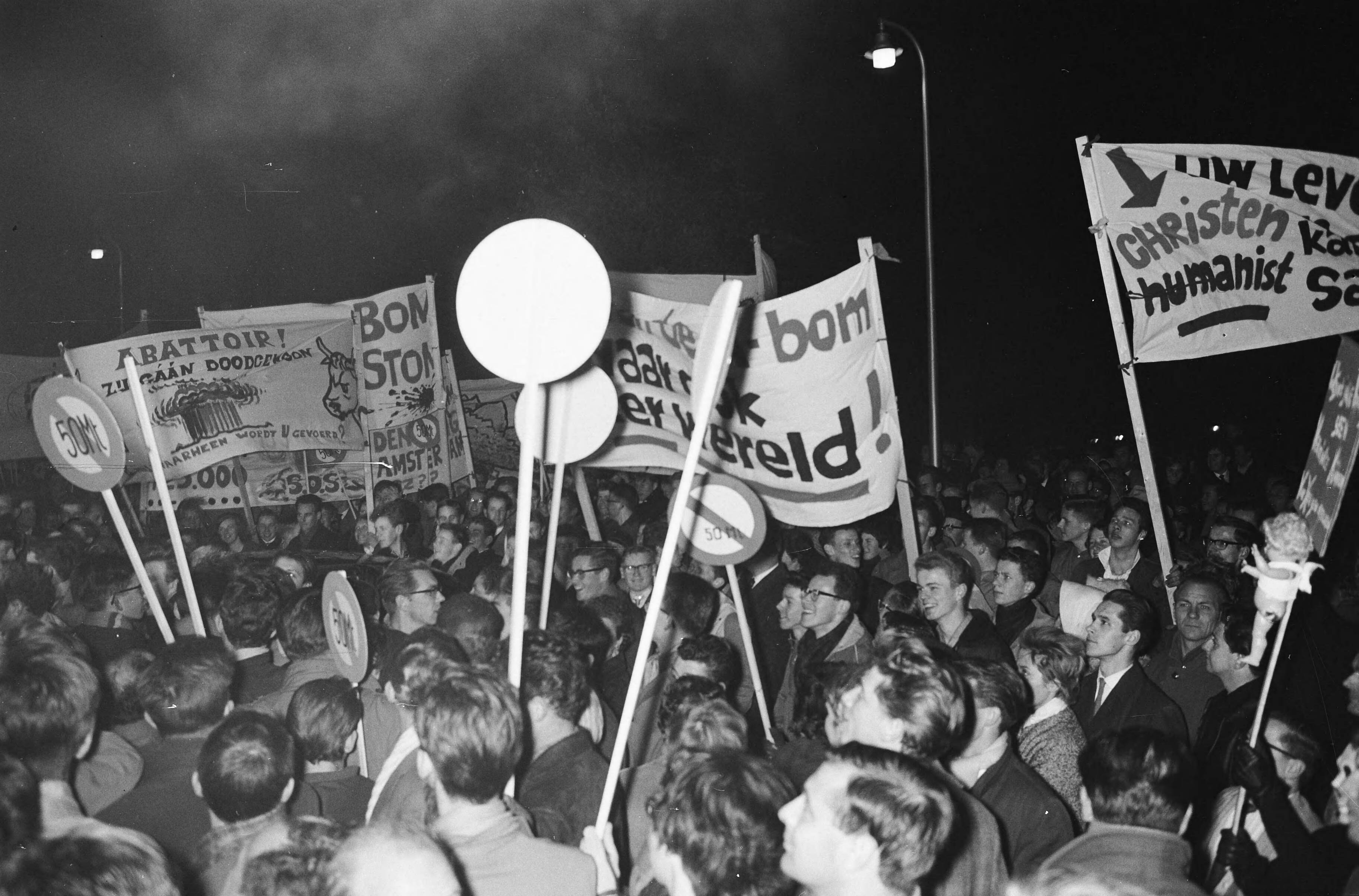 Fotocollectie Anefo — Betogers met spandoeken tijdens een anti-atoombomdemonstratie in Den Haag — Foto: Boer, […] de / Anefo. Licentie: Set B: Rechtenvrij / Publiek Domein. Bron: Nationaal Archief. http://hdl.handle.net/10648/a9e99844-d0b4-102d-bcf8-003048976d84