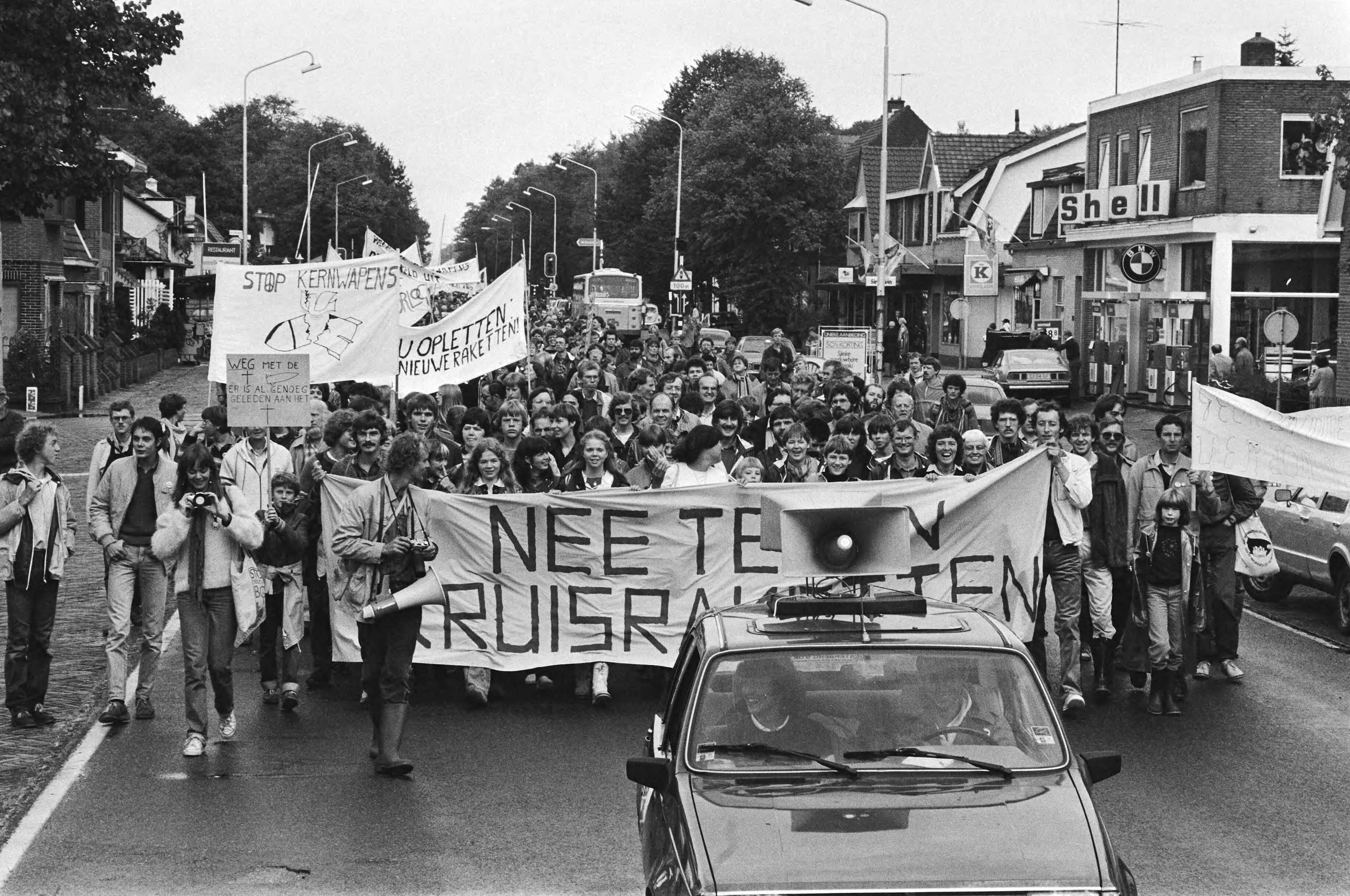 Jaarlijkse demonstratie tegen kernwapens in Soesterberg — Demonstranten achter een spandoek — Foto: Antonisse, Marcel / Anefo. Licentie: Set B: Rechtenvrij / Publiek Domein. Bron: Nationaal Archief. http://hdl.handle.net/10648/ad1fb700-d0b4-102d-bcf8-003048976d84