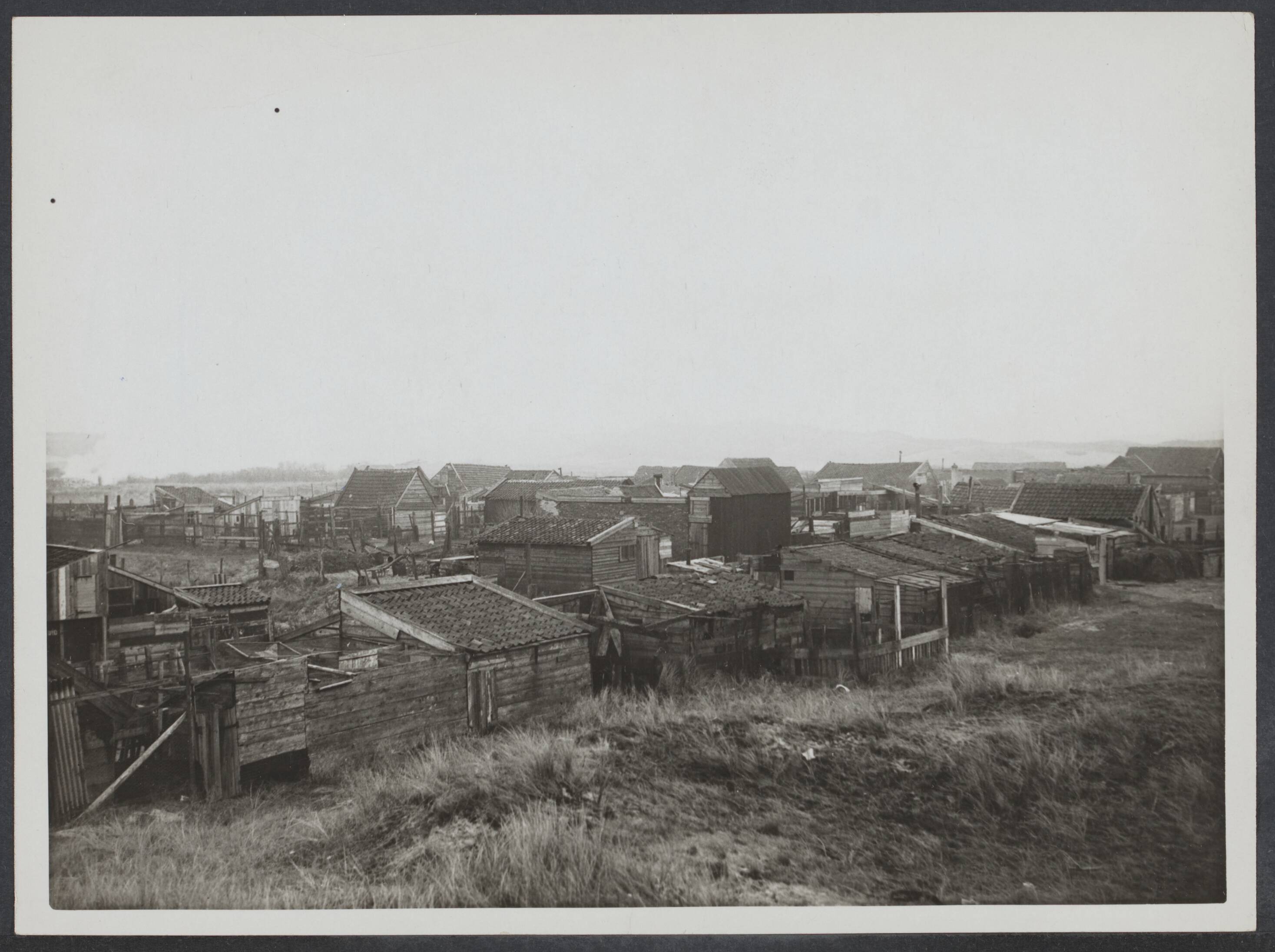 Zandvoort, vóór 1945 — Een kijkje in het Varkensdorp achter de begraafplaats bij Zandvoort. Het is het z.g. "Entos" terrein, een dorp op zichzelf., met varkens, kippen , konijnen, ezels enz. als bewoners. Overzicht van de uit alle mogelijke stukken hout, steen of ijzer vervaardigde huisjes — Foto: N.V. Polygoon. Licentie: Set B: Rechtenvrij / Publiek Domein. Bron: Nationaal Archief. http://hdl.handle.net/10648/b9381fa2-0a11-7a03-bd9c-2b34a82daca2