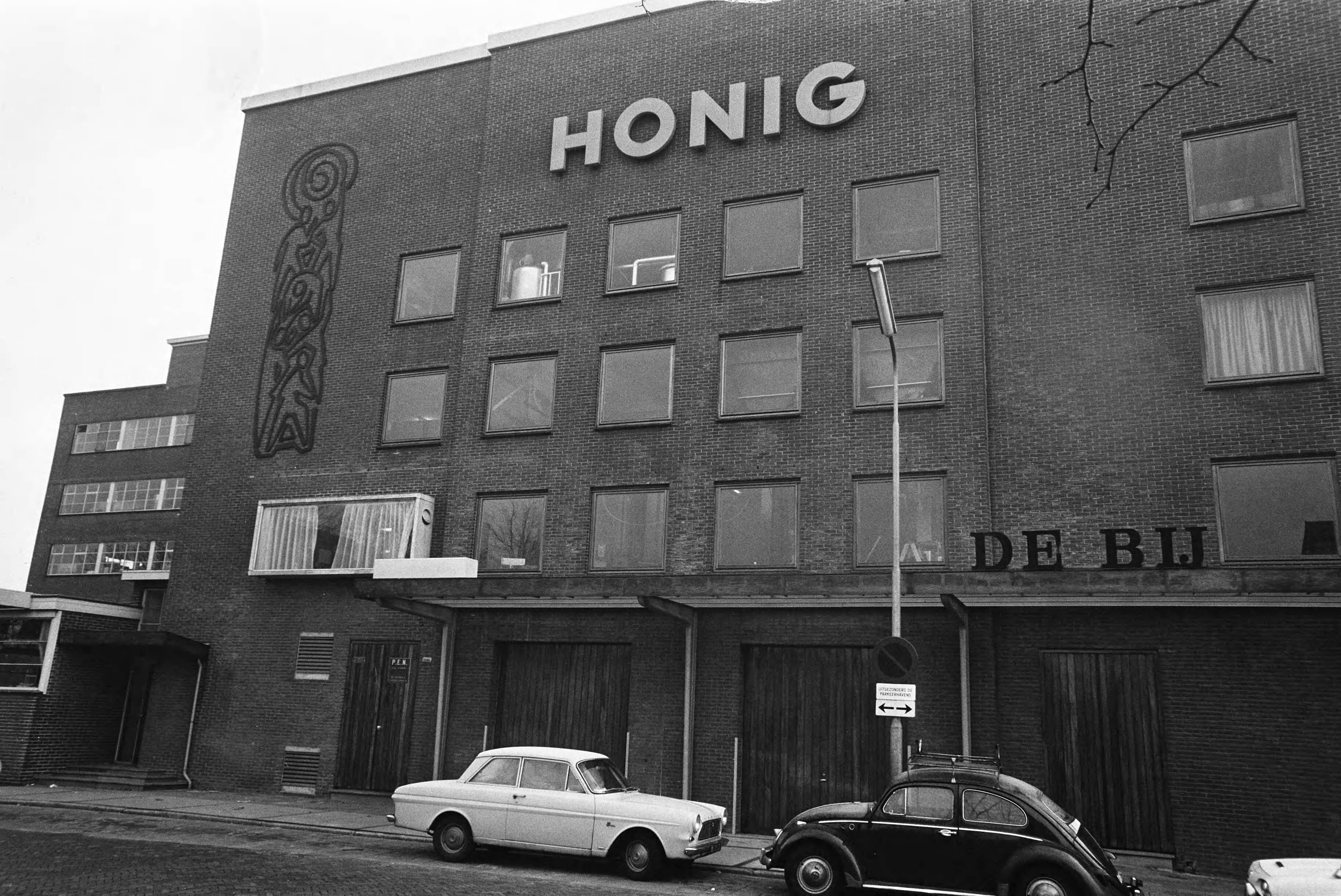 Fotocollectie Anefo — Werknemers van Honig in Koog aan de Zaan staken voor 1% duurtetoeslag en werktijdverkorting aan eind van de dag. Exterieur opschrift "Honig" — Foto: Evers, Joost / Anefo. Licentie: Set B: Rechtenvrij / Publiek Domein. Bron: Nationaal Archief. http://hdl.handle.net/10648/ab864210-d0b4-102d-bcf8-003048976d84