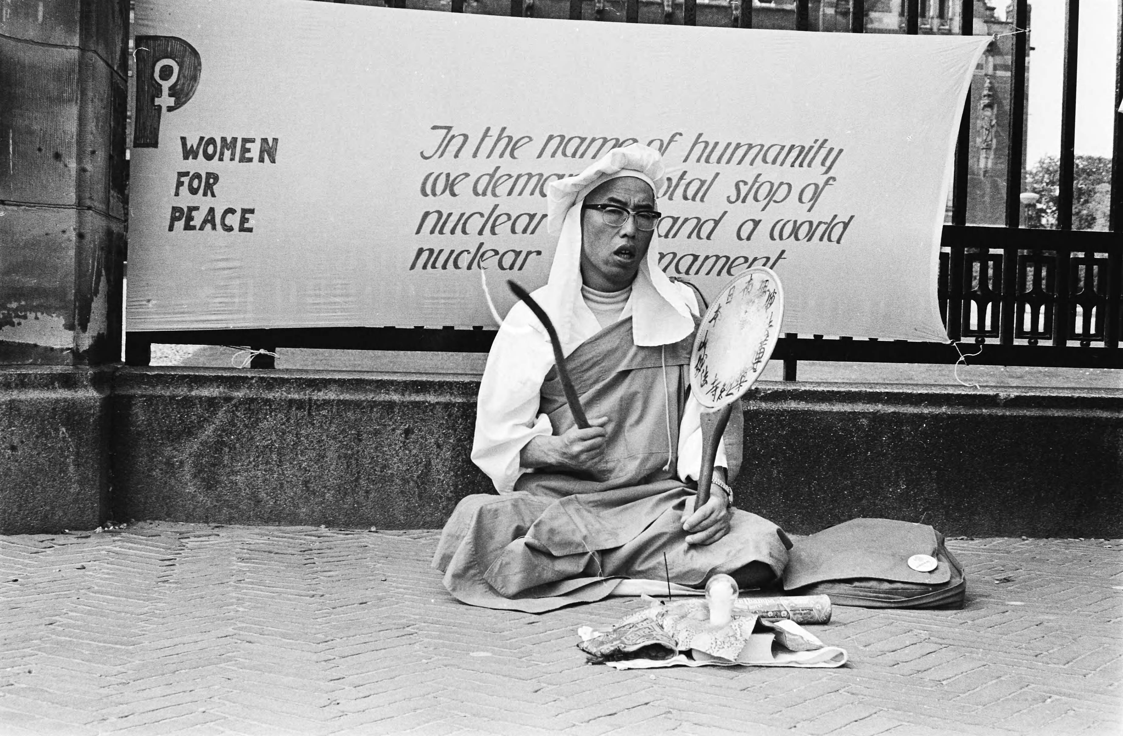 Fotocollectie Anefo — Demonstratie van Vrouwen voor Vrede voor het Vredespaleis in Den Haag omdat 35 jaar geleden een atoombom op Hiroshima viel: een biddende monnik — Foto: Dijk, Hans van / Anefo. Licentie: Set B: Rechtenvrij / Publiek Domein. Bron: Nationaal Archief. http://hdl.handle.net/10648/ace50cae-d0b4-102d-bcf8-003048976d84