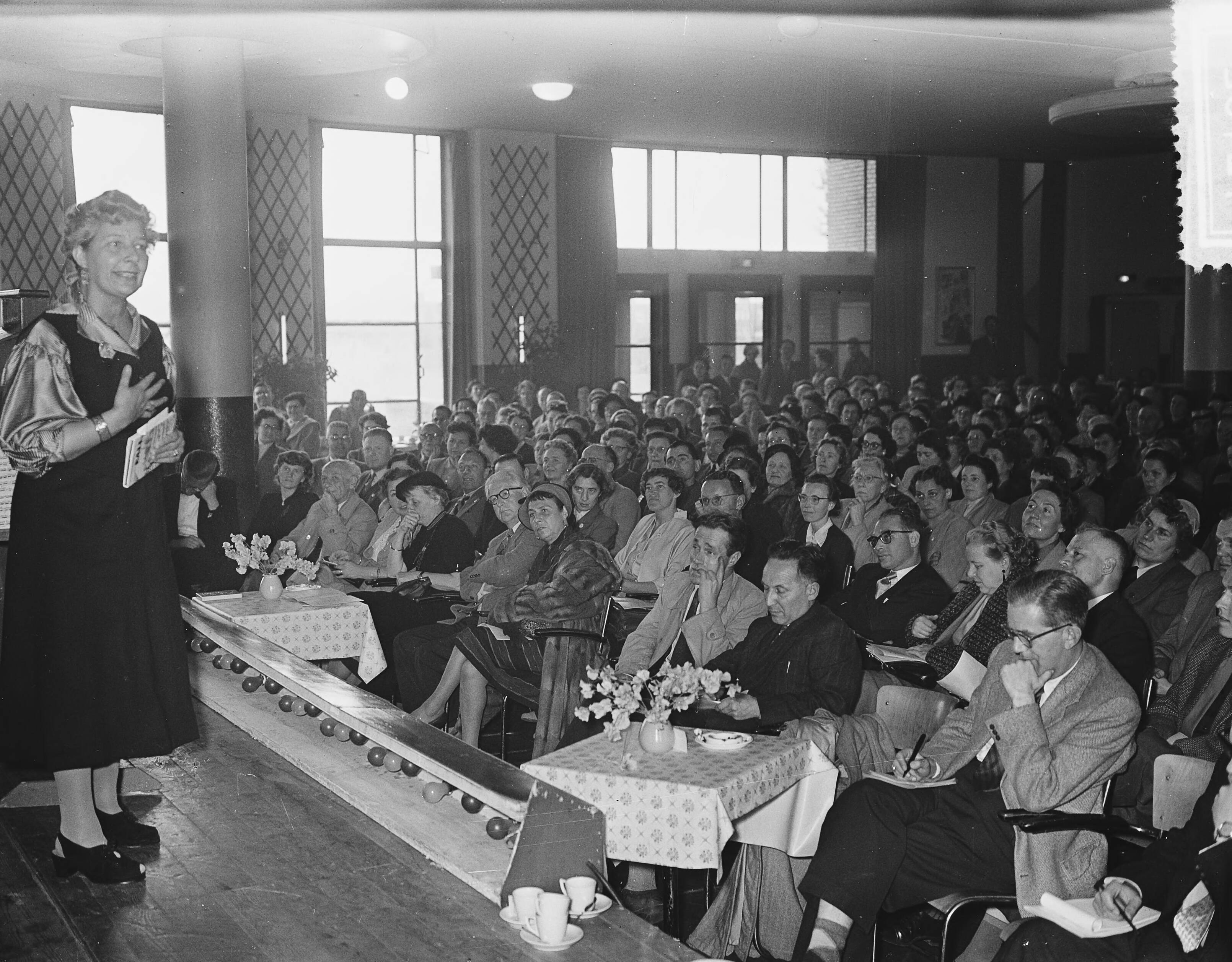 Fotocollectie Anefo — Wereld Vrijgezellendag in de Houtrusthallen te Den Haag. Mary Pos bracht een speciale boodschap uit Amerika — Foto: Bilsen, Joop van / Anefo. Licentie: Set B: Rechtenvrij / Publiek Domein. Bron: Nationaal Archief. http://hdl.handle.net/10648/a935907e-d0b4-102d-bcf8-003048976d84