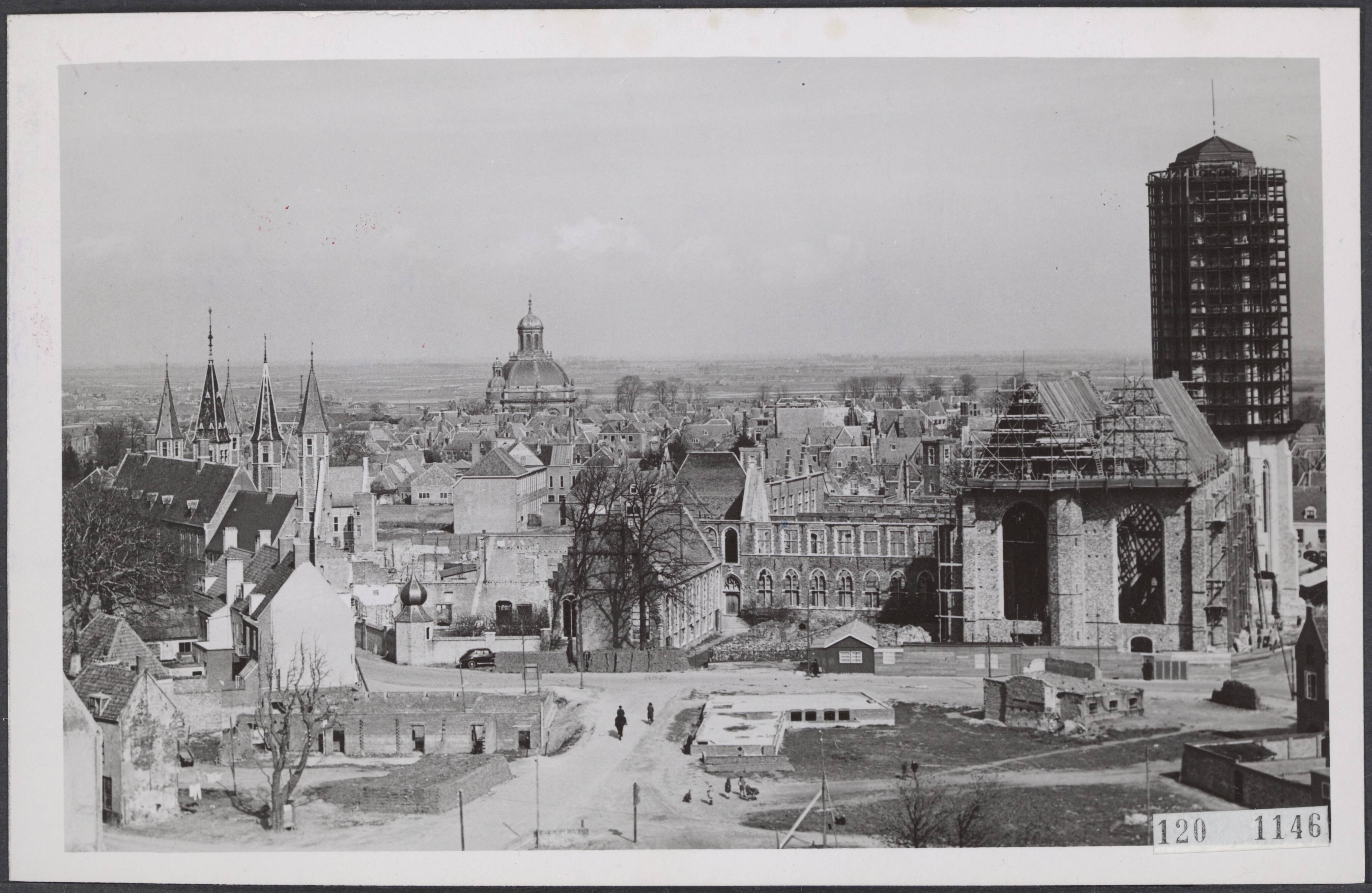 Fotocollectie Rijksvoorlichtingsdienst Eigen — Er wordt hard gewerkt aan de restauratie van de Lange Jan te Middelburg, welke tijdens de oorlog door brand werd vernield. Rechts op de foto geheel in steigers gehulde Lange Jan, links de torentjes van de beroemde Abdij — Foto: Moedrik, D. / Anefo. Licentie: Set B: Rechtenvrij / Publiek Domein. Bron: Nationaal Archief. http://hdl.handle.net/10648/af231916-d0b4-102d-bcf8-003048976d84