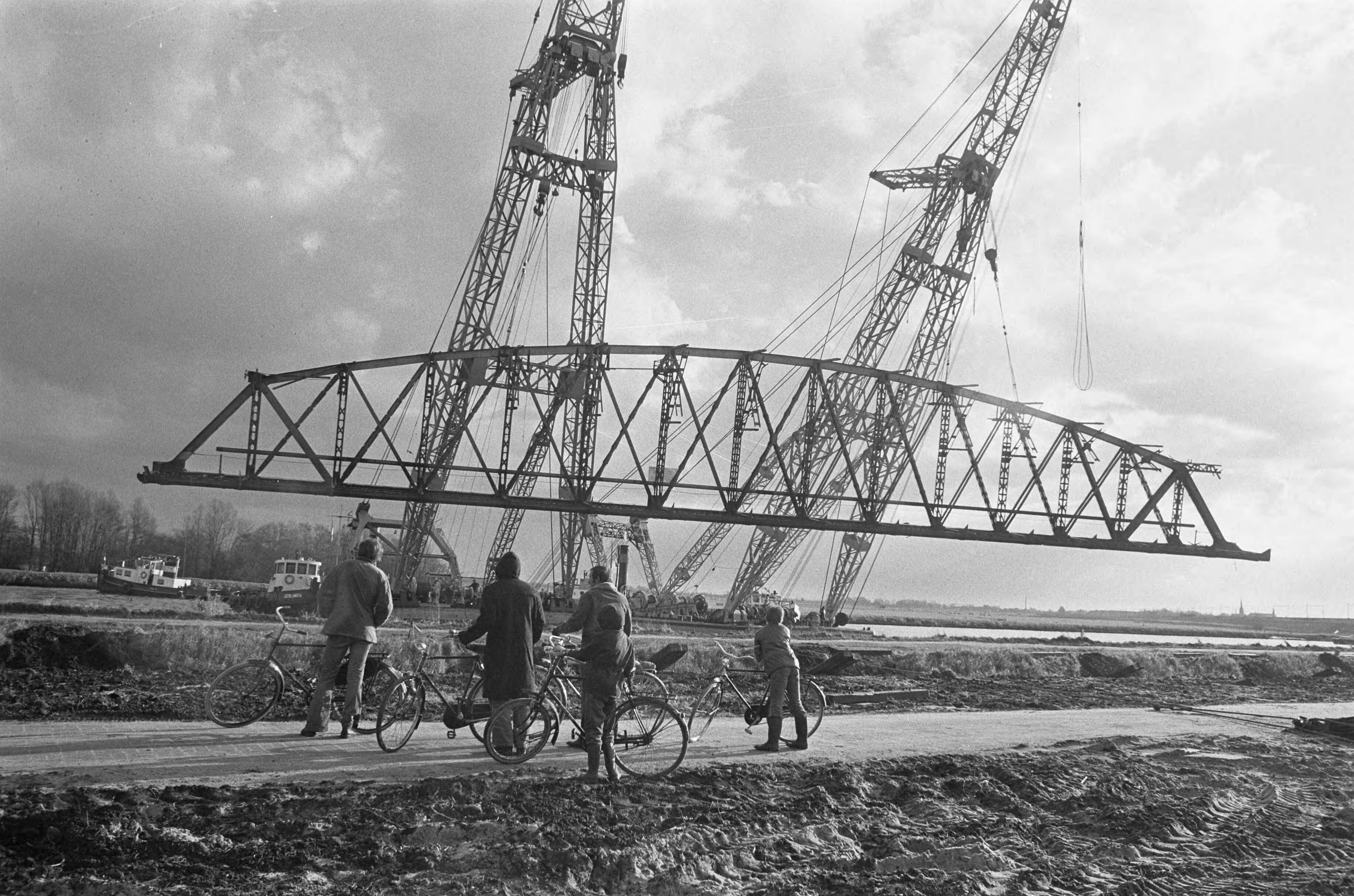 Oude spoorbrug over het Amsterdam -Rijnkanaal wordt opgeruimd — Fietsers bekijken de werkzaamheden: de brug hangt in de takels — Foto: Fotograaf Onbekend / Anefo. Licentie: Set B: Rechtenvrij / Publiek Domein. Bron: Nationaal Archief. http://hdl.handle.net/10648/ac3d5dce-d0b4-102d-bcf8-003048976d84