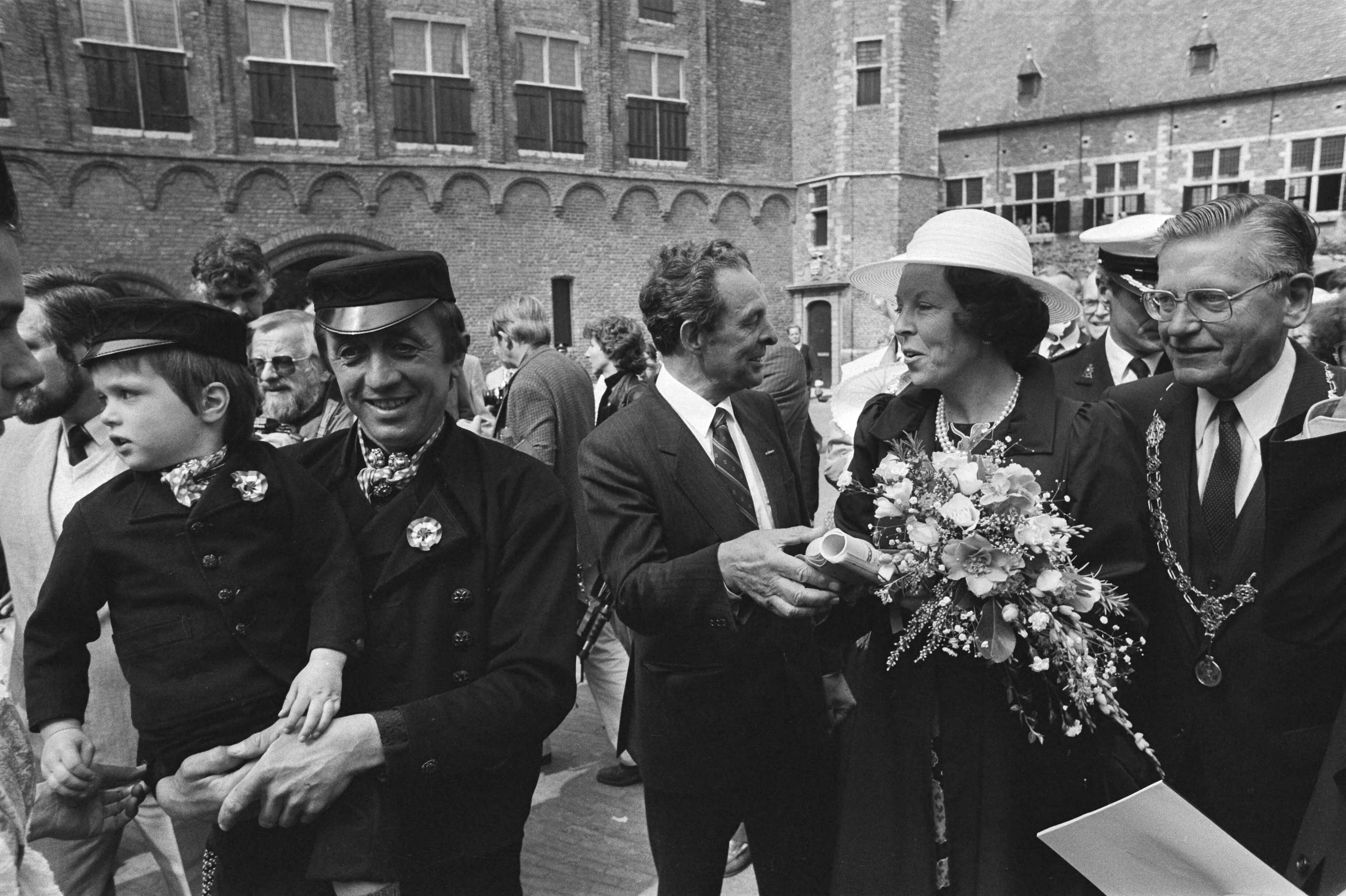 Fotocollectie Anefo — Koningin Beatrix en Prins Claus bij Nationale herdenkingsmanifestatie in Middelburg; Koningin Beatrix met links vader en zoon in klederdracht / — Foto: Bogaerts, Rob / Anefo. Licentie: Set B: Rechtenvrij / Publiek Domein. Bron: Nationaal Archief. http://hdl.handle.net/10648/ad385936-d0b4-102d-bcf8-003048976d84