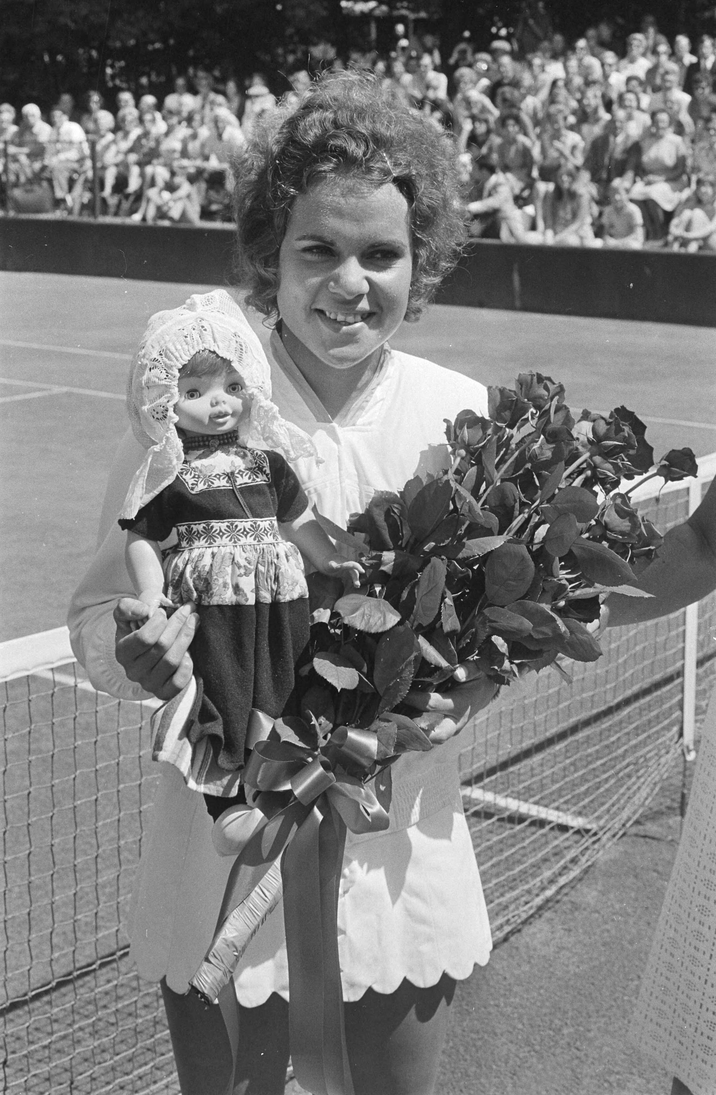 Fotocollectie Anefo — Internationale tenniskampioenschappen te Hilversum, Evonne Goolagong met Volendammer pop (gekregen voor verjaardag) — Foto: Punt, W. / Anefo. Licentie: Set B: Rechtenvrij / Publiek Domein. Bron: Nationaal Archief. http://hdl.handle.net/10648/abc86ea6-d0b4-102d-bcf8-003048976d84
