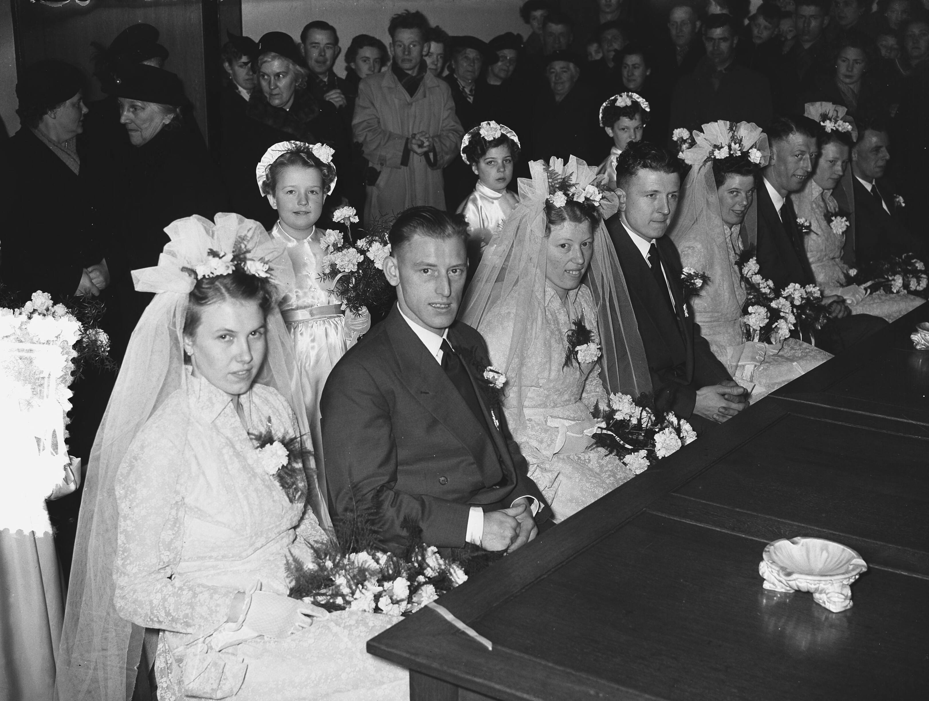 Fotocollectie Anefo — Meervoudige bruiloft. Op het gemeentehuis van Leimuiden trouwden vier telgen uit het gezin Brand (15 kinderen) tegelijkertijd. Vlnr. Het zijn van links naar rechts: Toon Brand (28 jaar, chauffeur) en Catharina Lemmens, Nellie Brand (23 jaar) en Theo Obdam (timmerman), Bram Brand (26 jaar, metselaar) en Bep Könst, en Dora Brand (24 jaar) en Kees Könst (bloemist) — Foto: Pot, Harry / Anefo. Licentie: Set B: Rechtenvrij / Publiek Domein. Bron: Nationaal Archief. http://hdl.handle.net/10648/a930cb34-d0b4-102d-bcf8-003048976d84