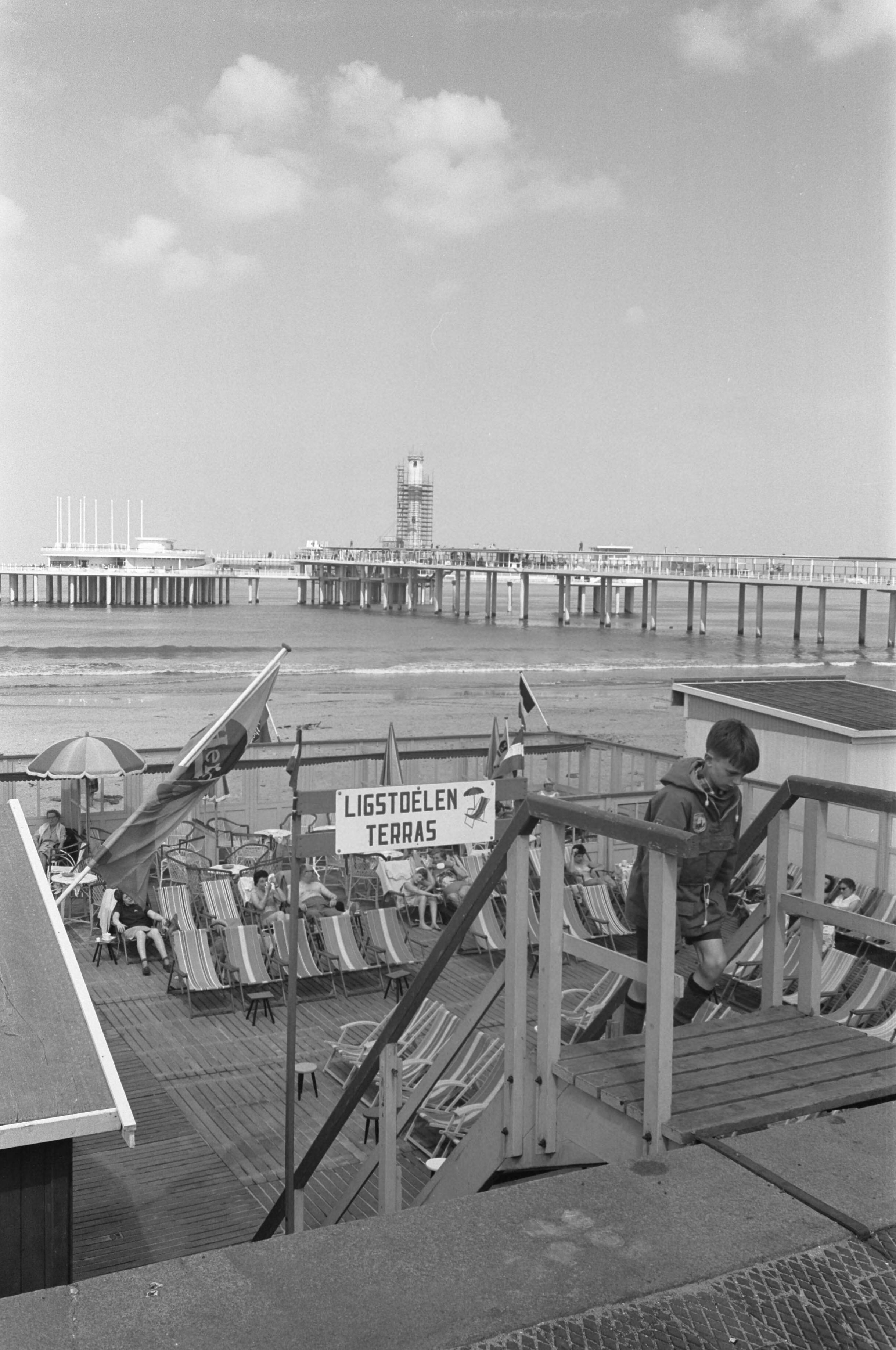 Fotocollectie Anefo — De nieuwe Pier in Scheveningen. Strandbeeld met in de achtergrond de nieuwe pier in aanbouw — Foto: Pot, Harry / Anefo. Licentie: Set B: Rechtenvrij / Publiek Domein. Bron: Nationaal Archief. http://hdl.handle.net/10648/a9d2e356-d0b4-102d-bcf8-003048976d84