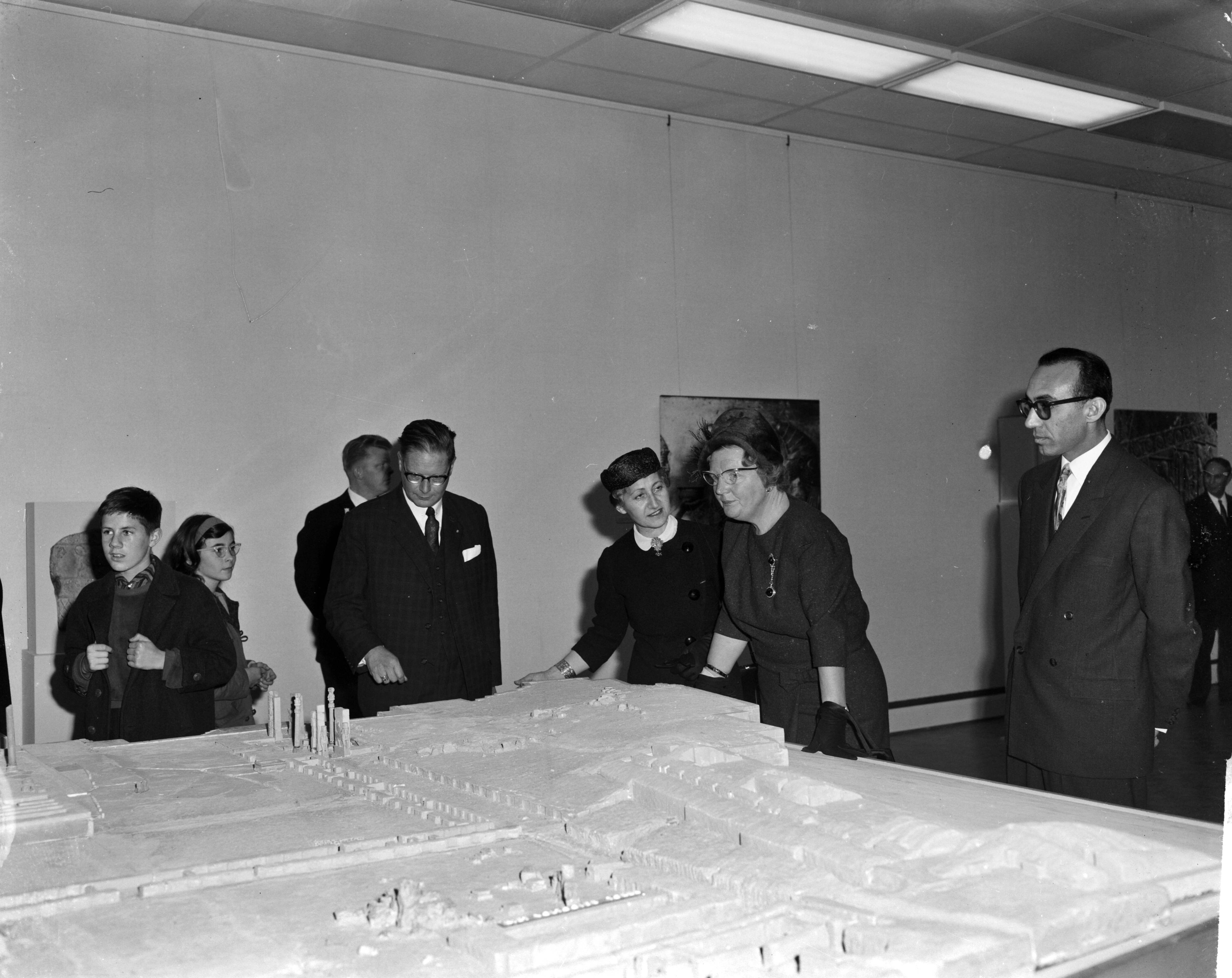 Fotocollectie Anefo — Koningin Juliana brengt een bezoek aan de tentoonstelling 7000 jaar Perzische Kunst te Den Haag, v.l.n.r. Louis Wijsenbeek (directeur), mevrouw Moghun, de koningin en dr. Ferydoun bij een maquette van Persepolis — Foto: Bilsen, Joop van / Anefo. Licentie: Set B: Rechtenvrij / Publiek Domein. Bron: Nationaal Archief. http://hdl.handle.net/10648/aa1dbb74-d0b4-102d-bcf8-003048976d84